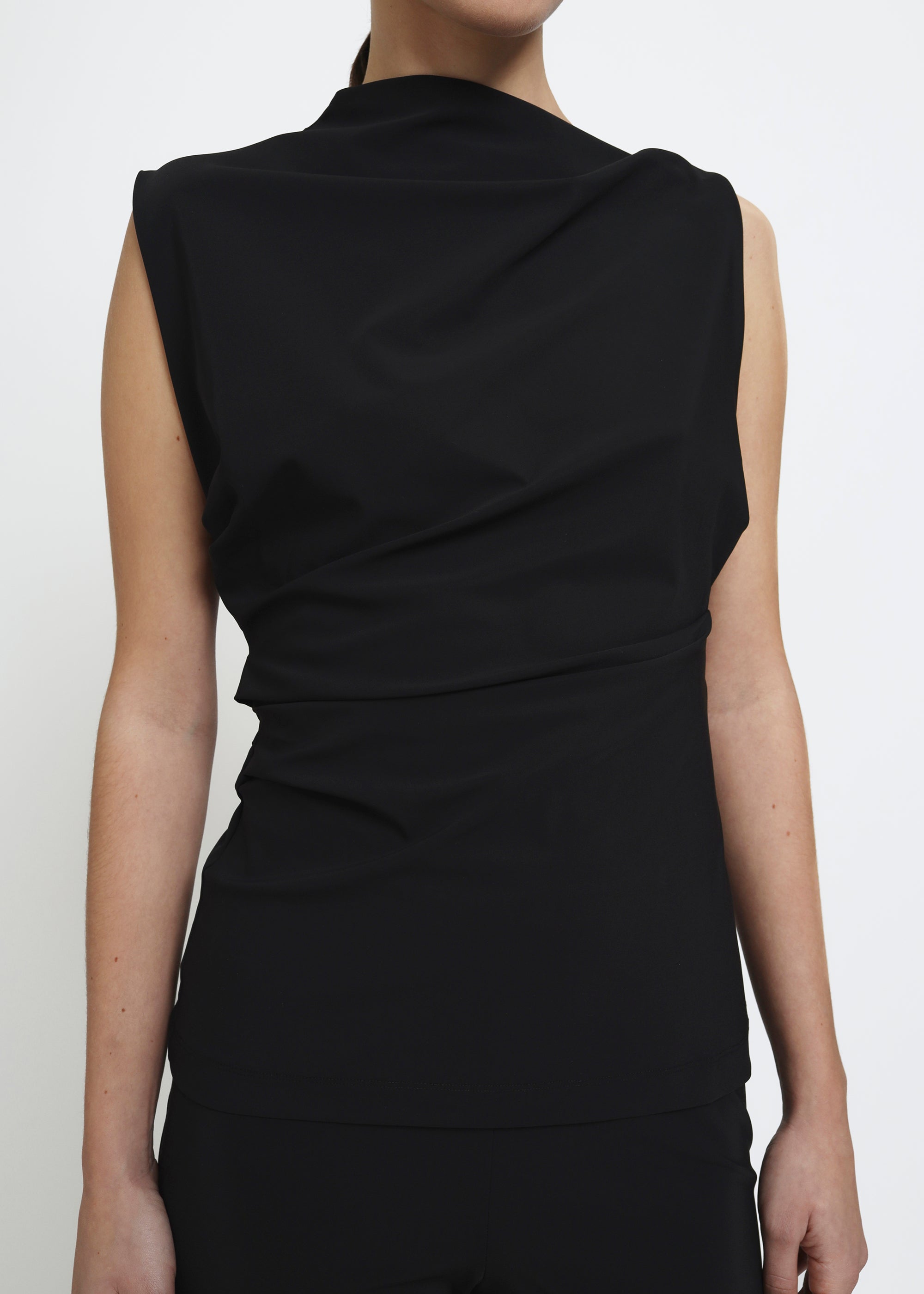 Black sleeveless top with an asymmetrical neckline and side waist folds