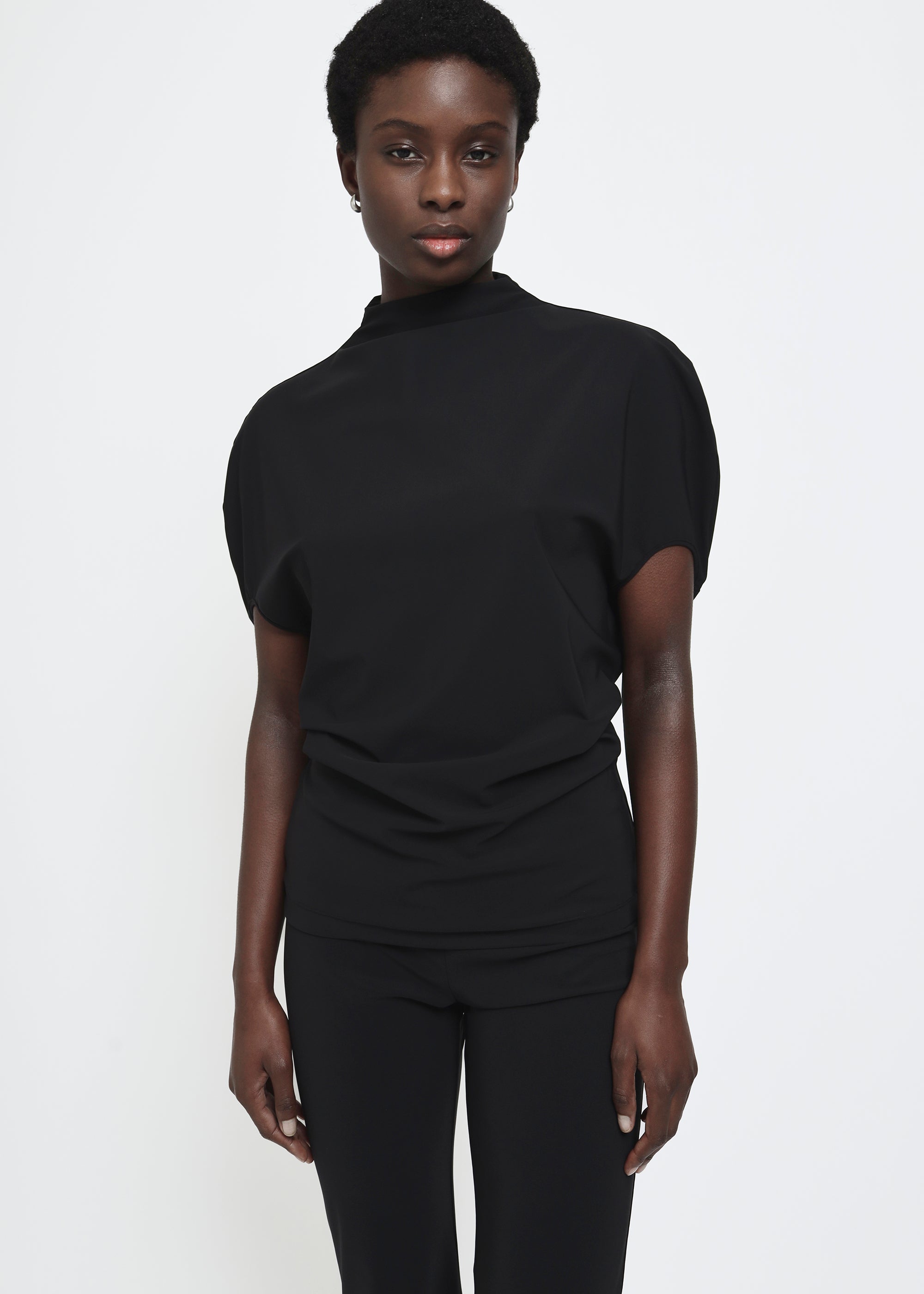 A black short-sleeve mock neck top with puffed circle sleeves and a gathered, draped waist detail.