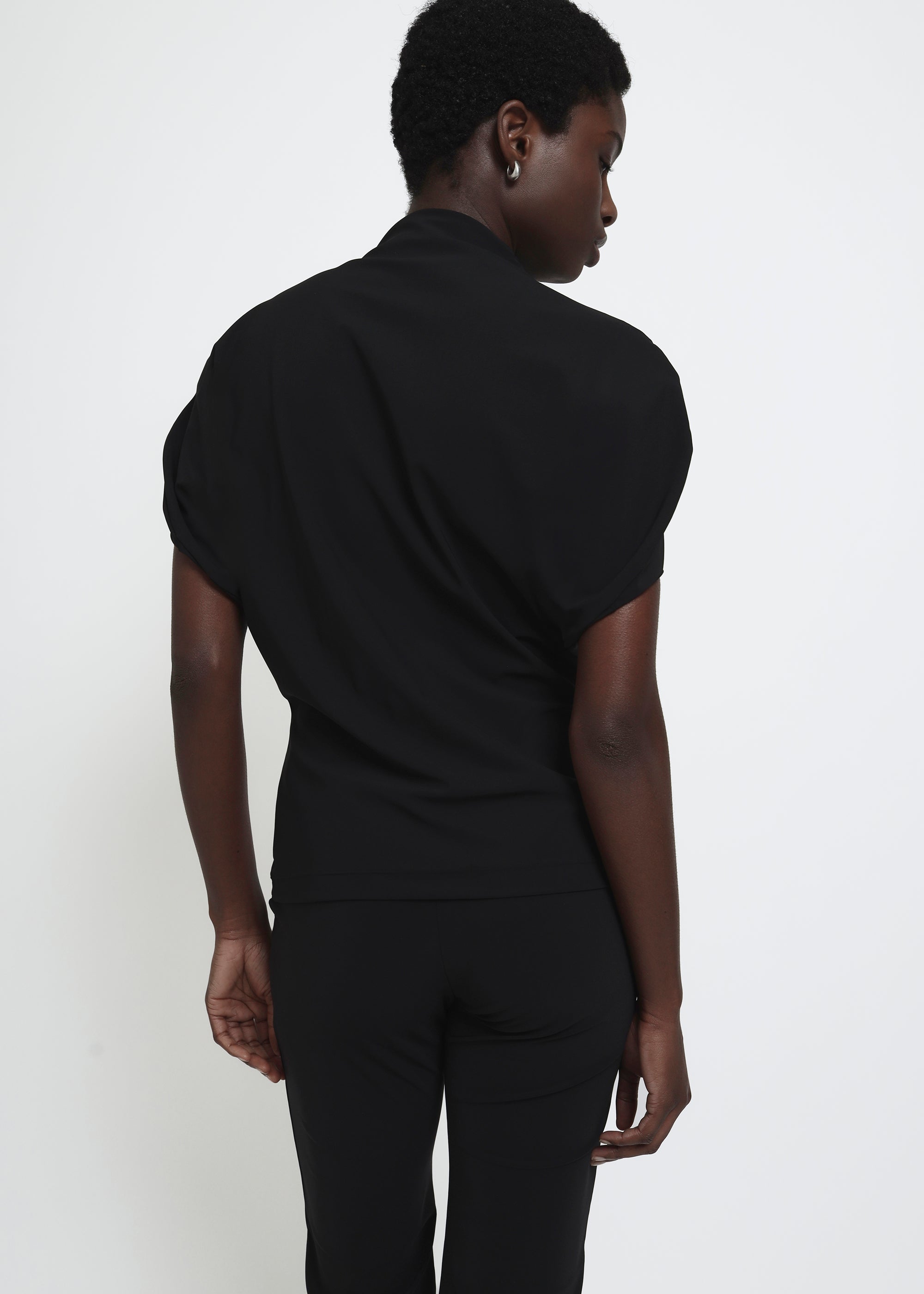 A black short-sleeve mock neck top with puffed circle sleeves and a gathered, draped waist detail.