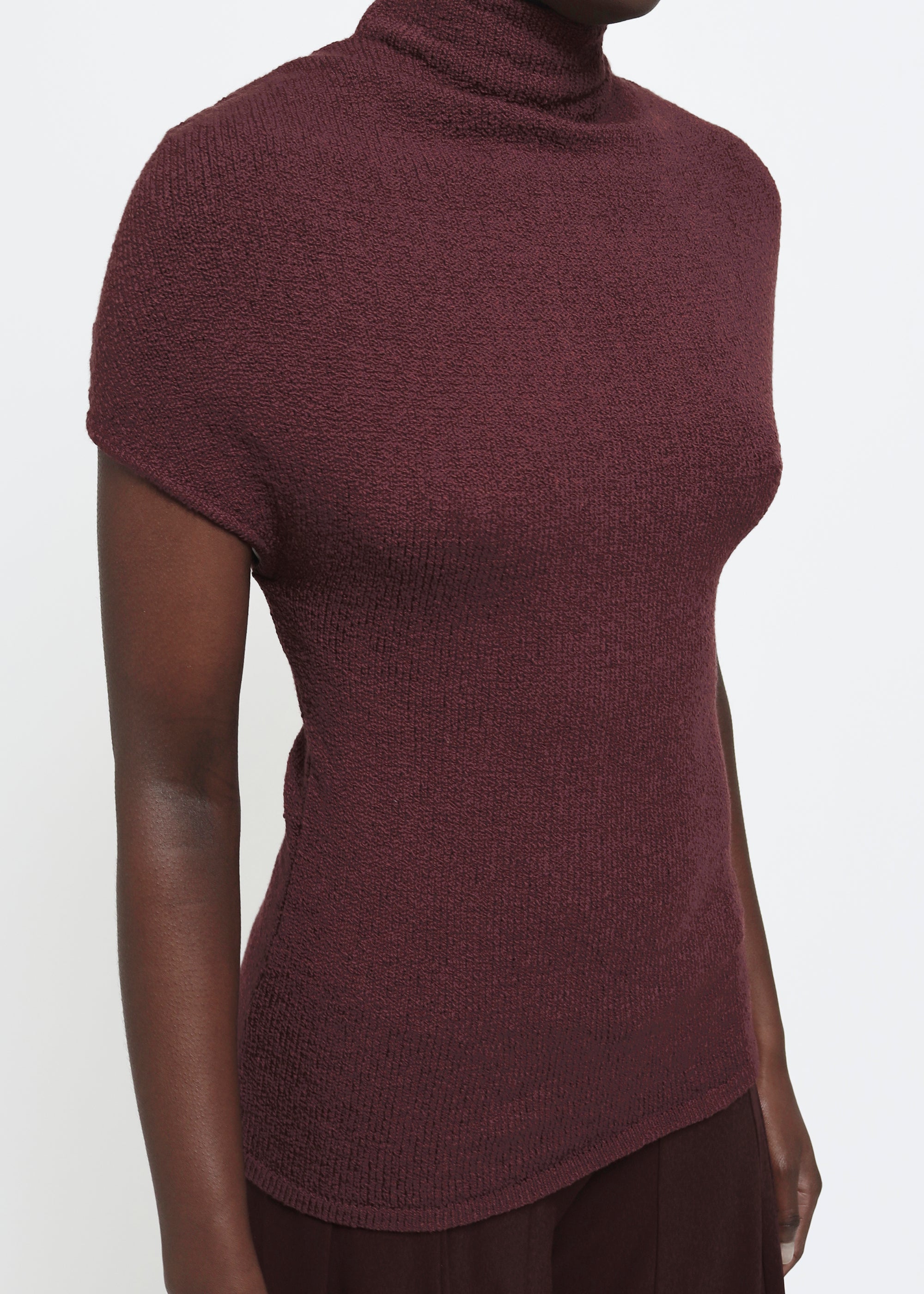 A wine colored cap-sleeve mock neck top in a textured bouclé like yarn.