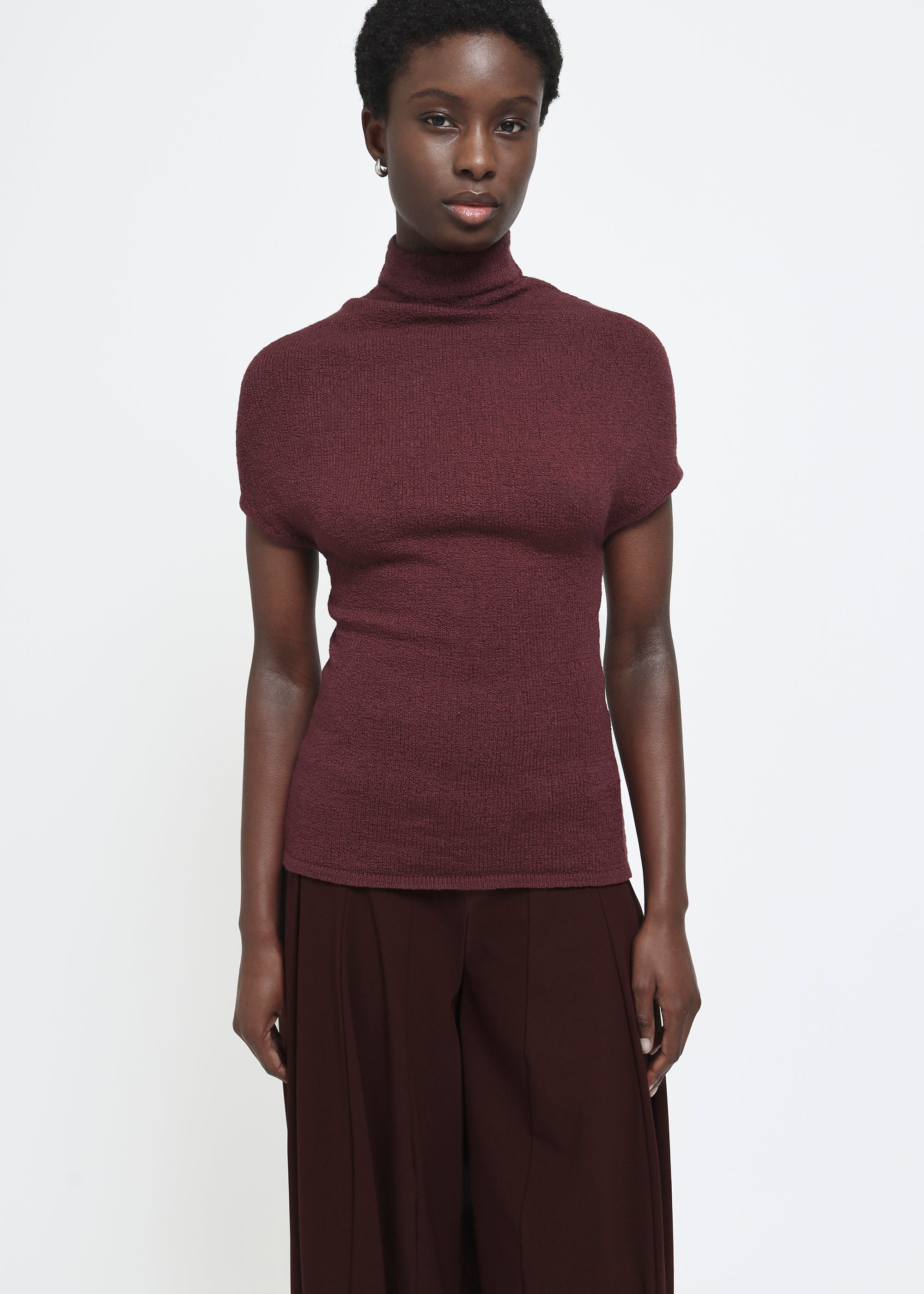 A wine colored cap-sleeve mock neck top in a textured bouclé like yarn.
