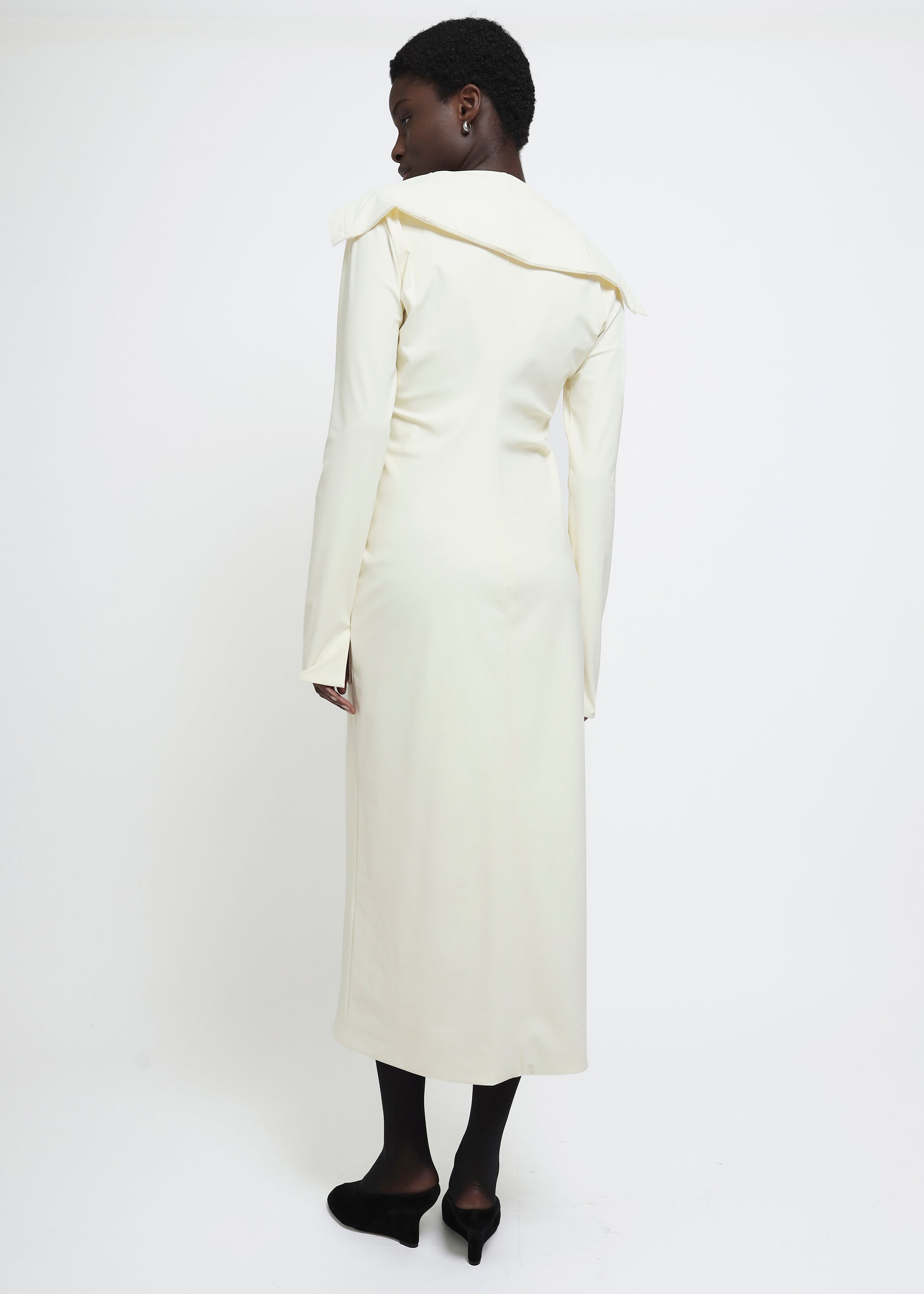 A long-sleeved cream-colored button-up dress with a wide collar.