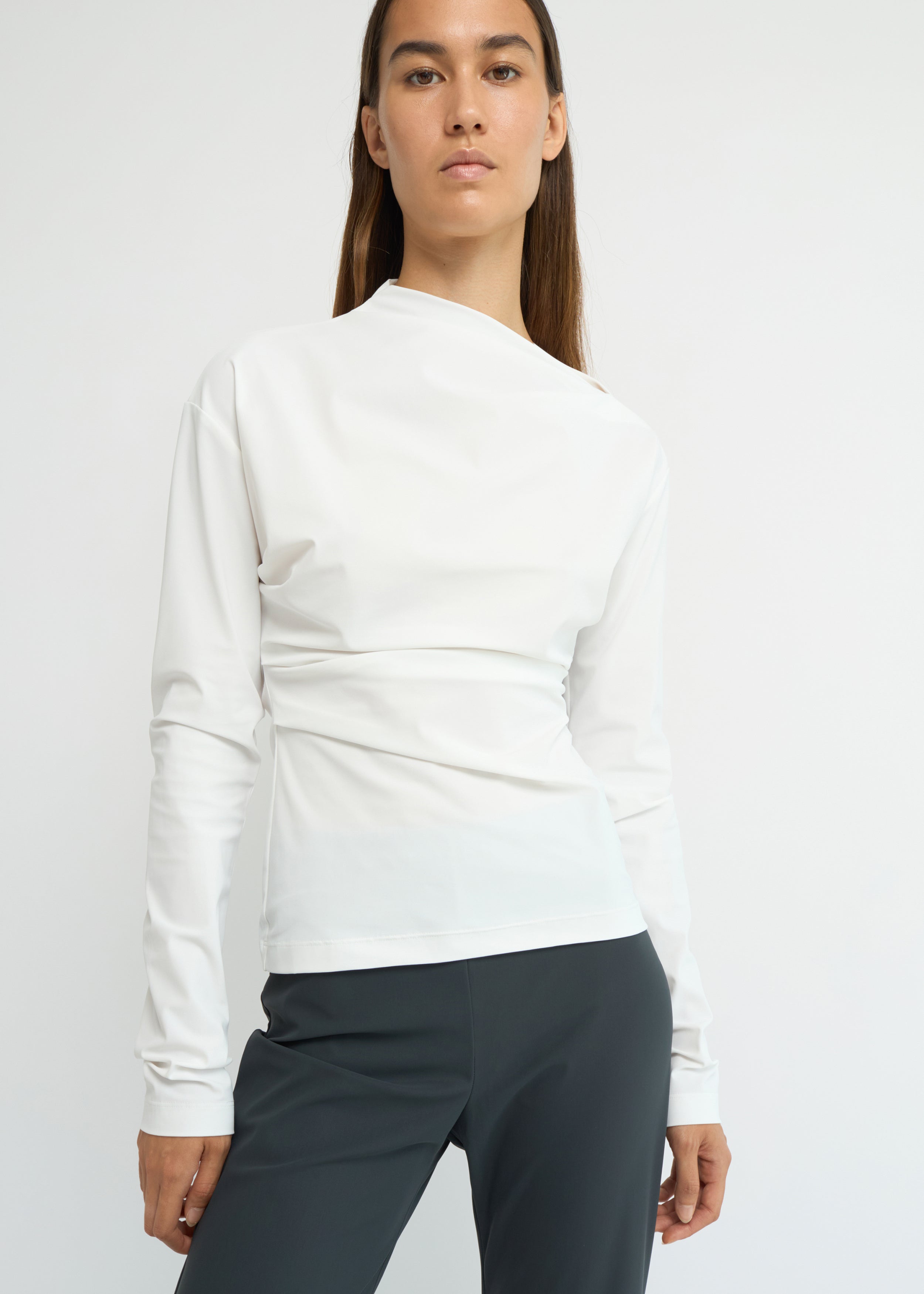 Off-white long-sleeve top with an asymmetrical neckline and soft waist folds