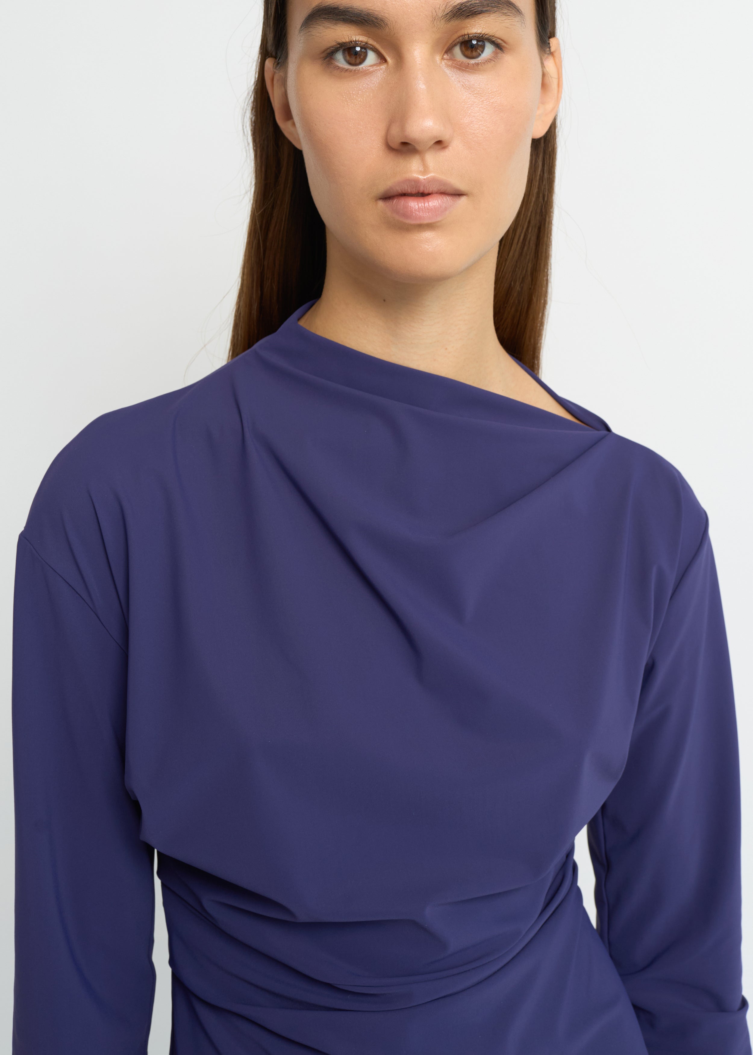 Violet long-sleeve top with an asymmetrical neckline and soft waist folds