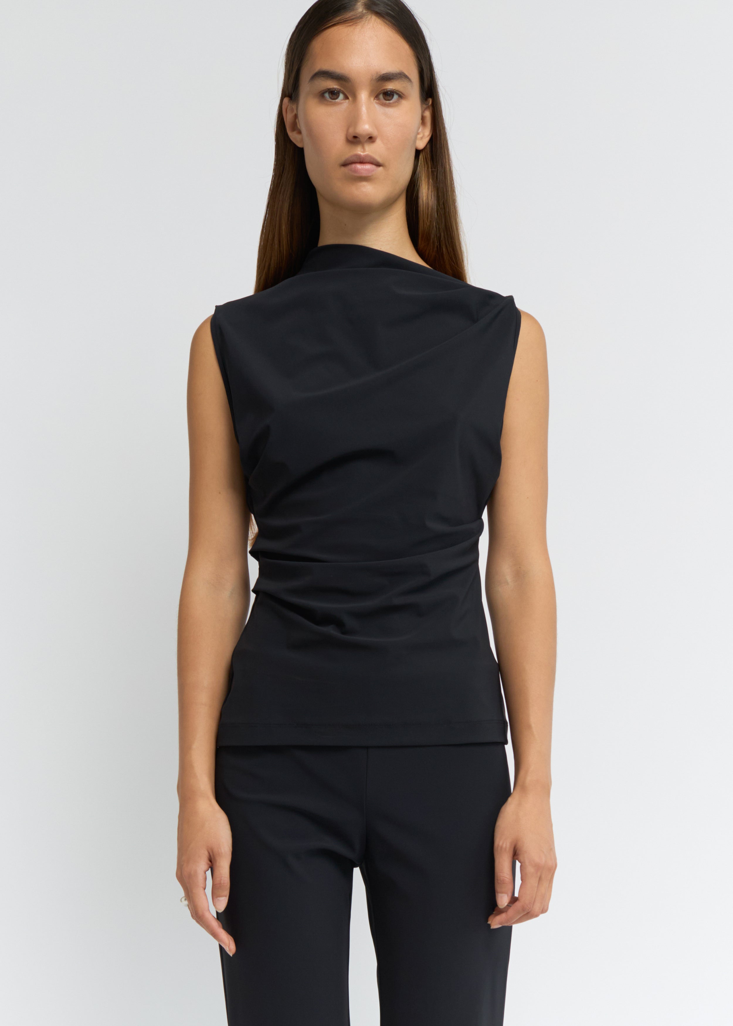 Black sleeveless top with an asymmetrical neckline and side waist folds
