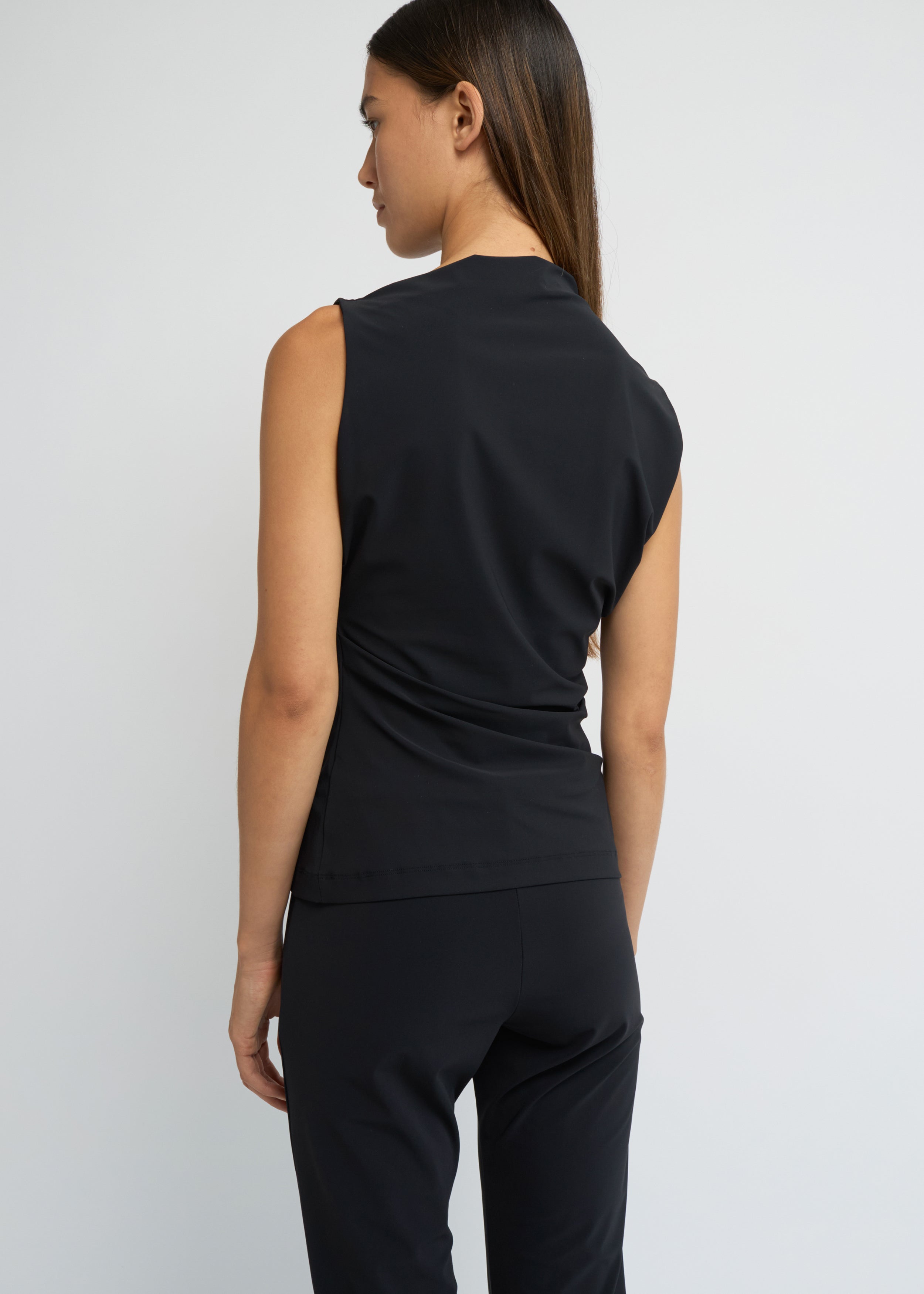 Black sleeveless top with an asymmetrical neckline and side waist folds