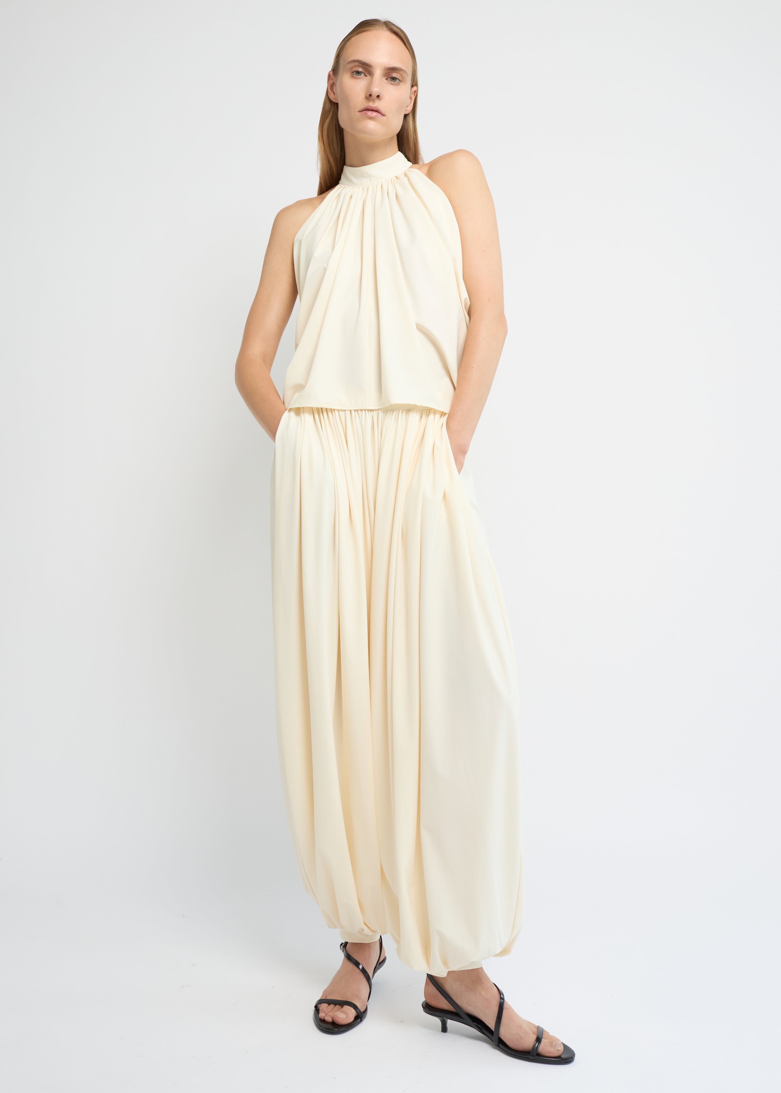 Cream balloon pants with a voluminous gathered silhouette and cuffed hems