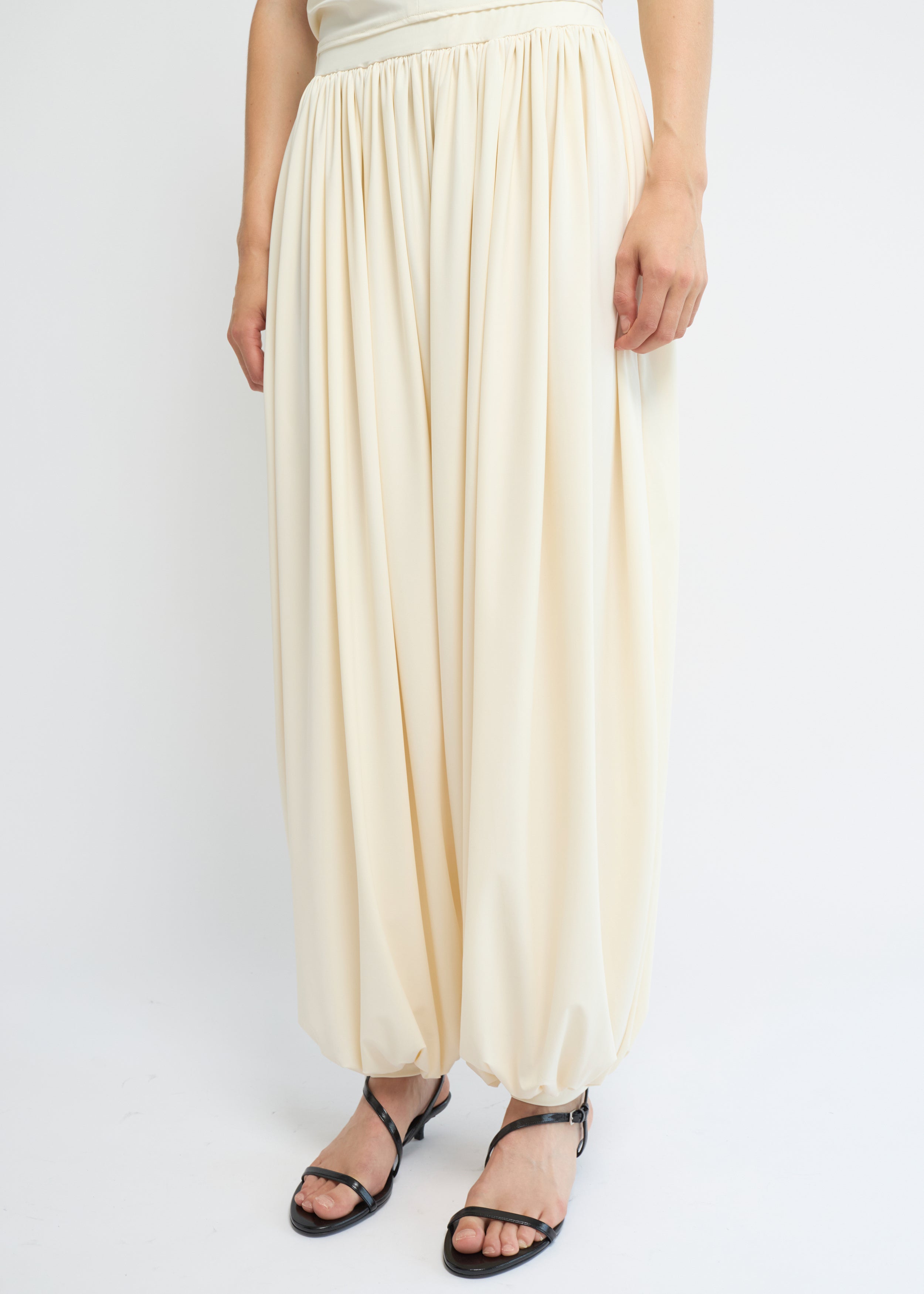 Cream balloon pants with a voluminous gathered silhouette and cuffed hems