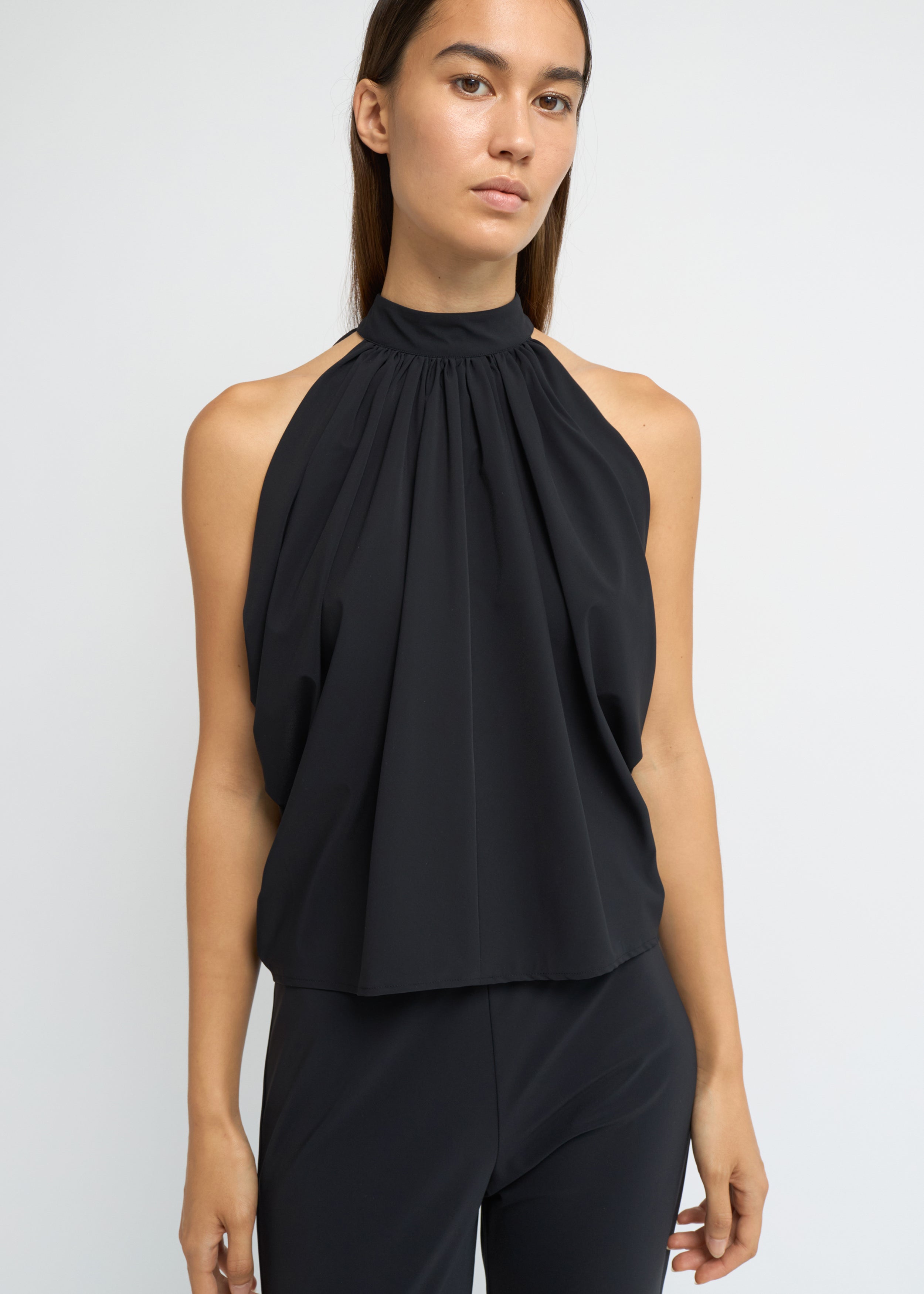 Black sleeveless balloon top with a gathered high neckline and voluminous silhouette