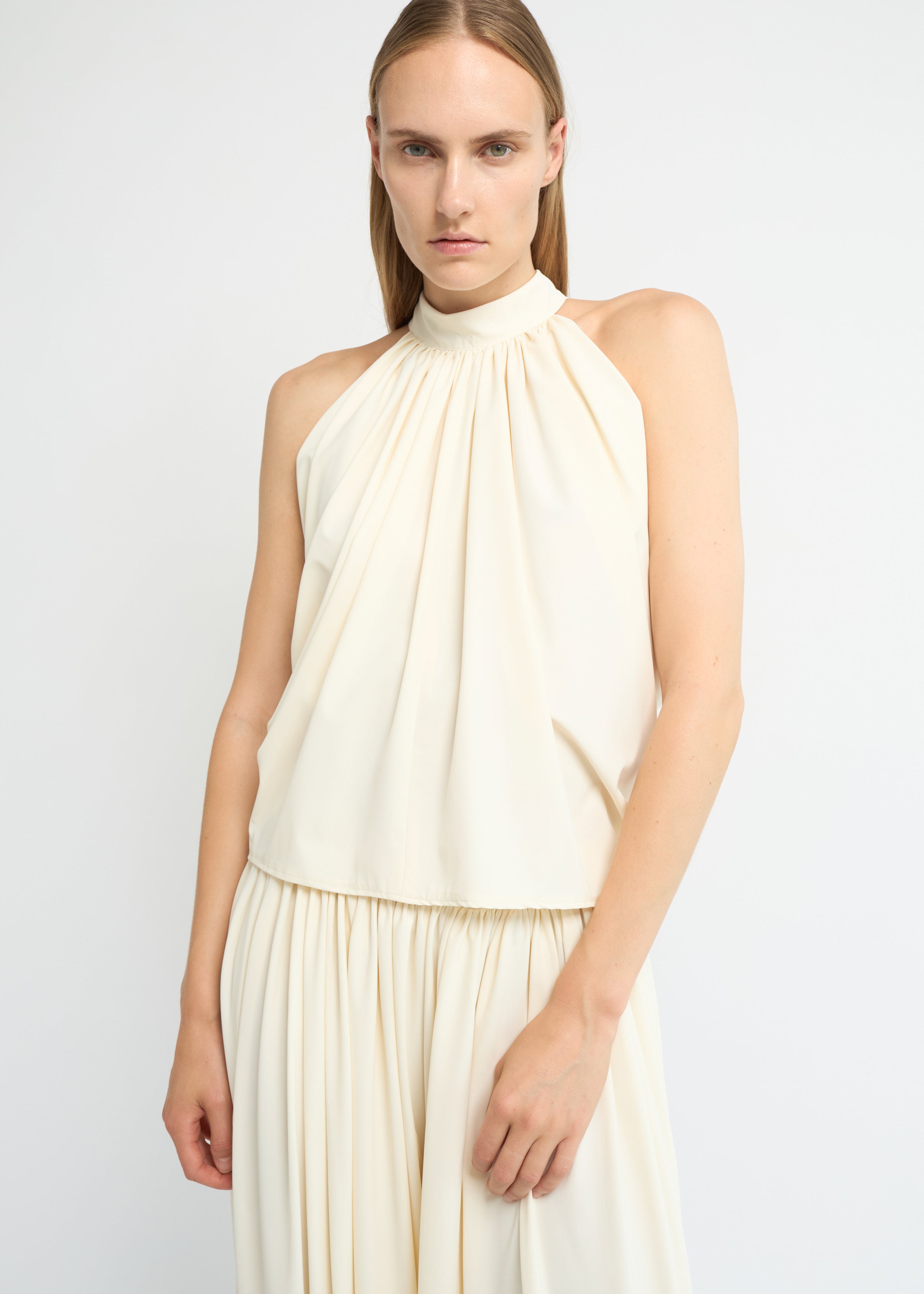 Cream sleeveless balloon top with a gathered high neckline and voluminous silhouette