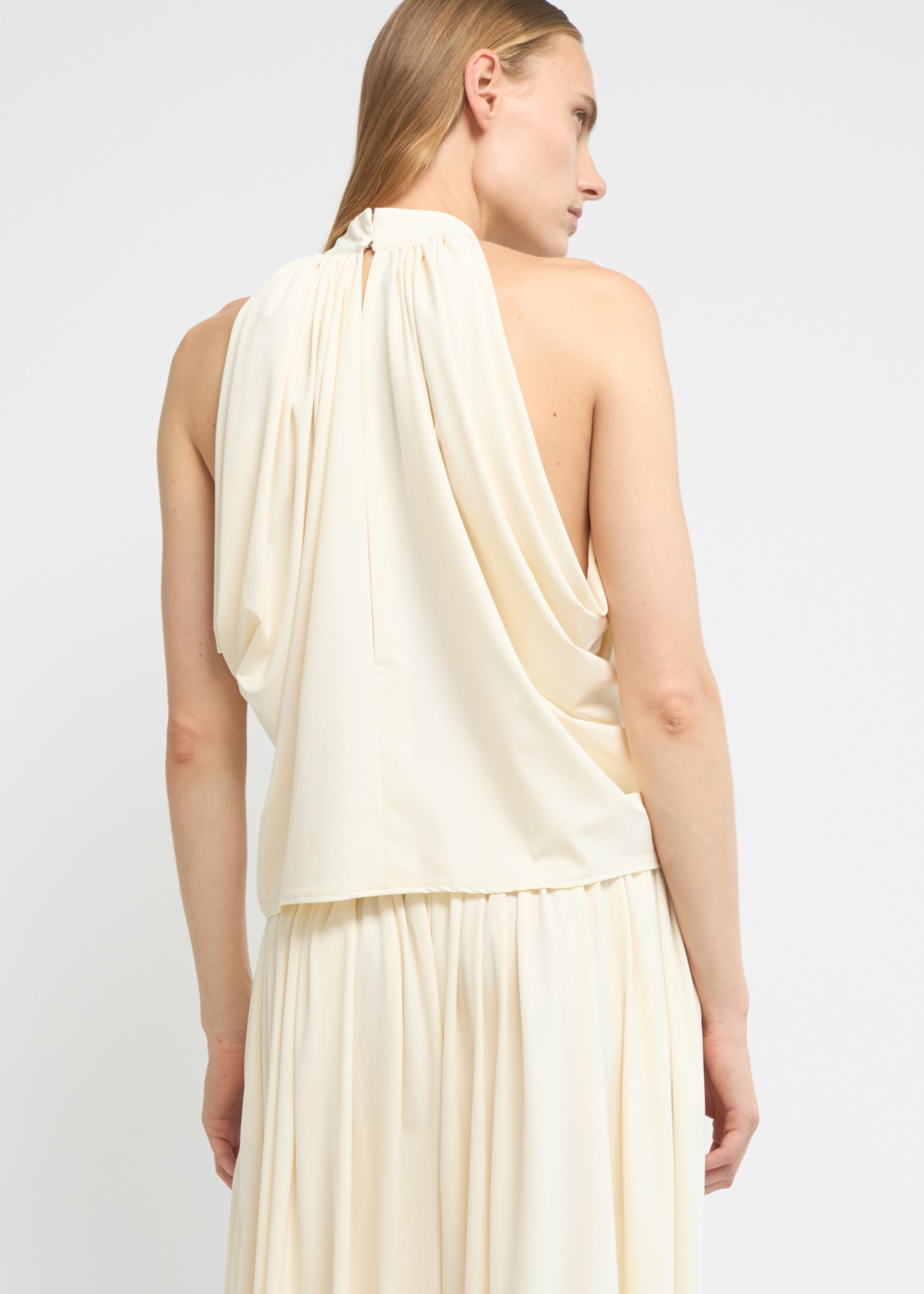 Cream sleeveless balloon top with a gathered high neckline and voluminous silhouette