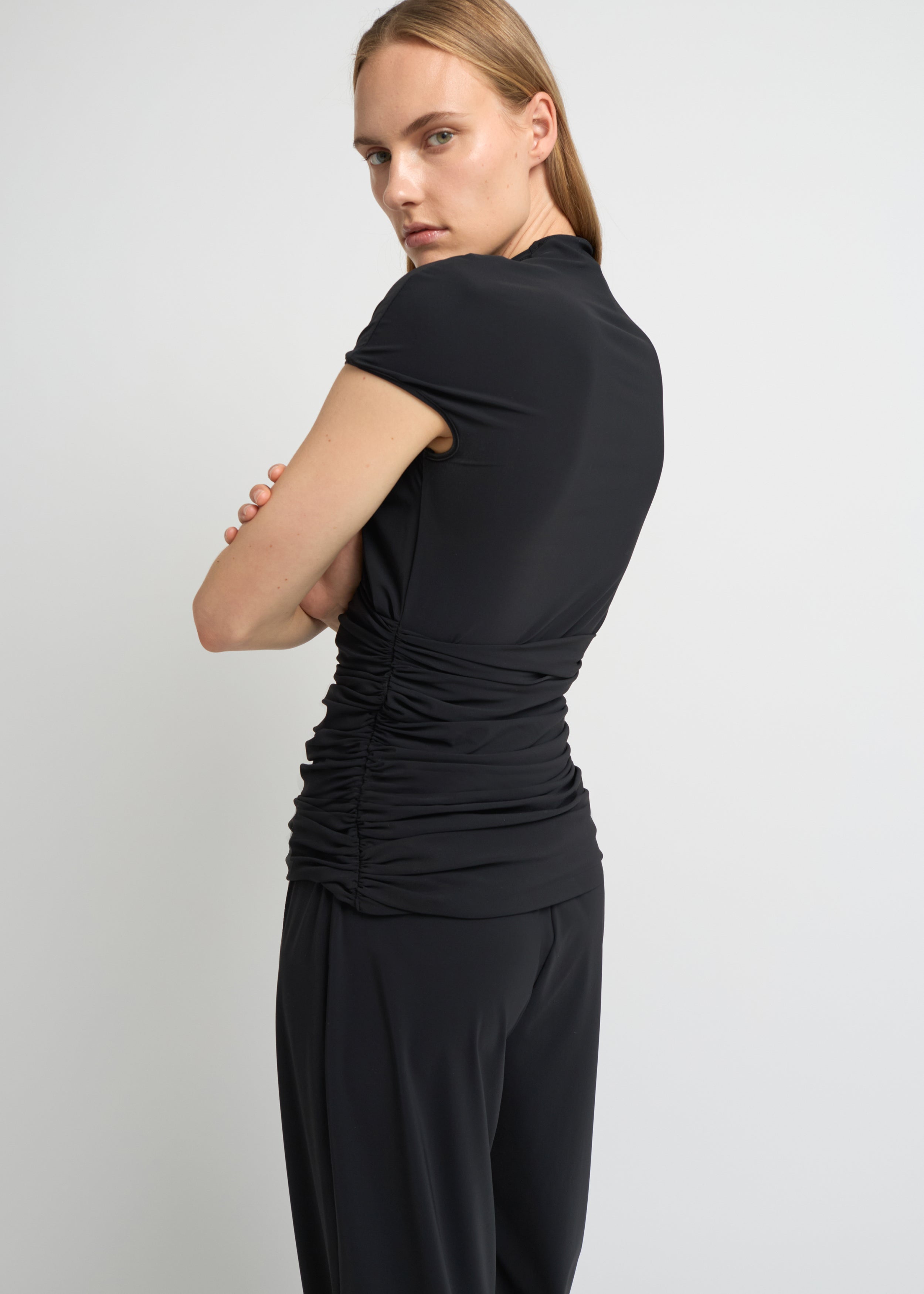 Black fitted short-sleeve top with a high neckline and soft gathers at the waist