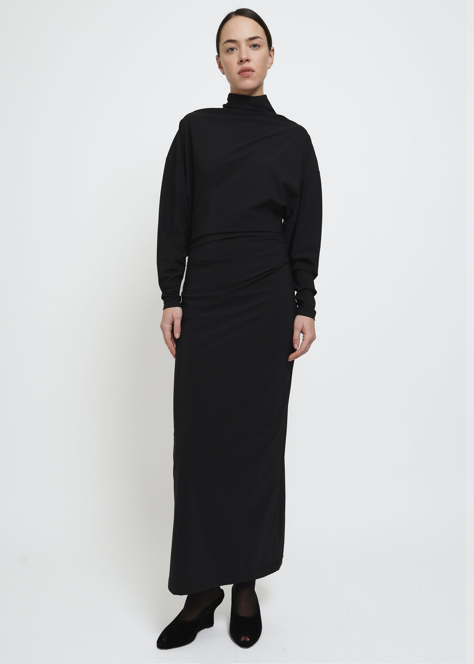 A long-sleeved black mock-neck midi dress with a draped waist.