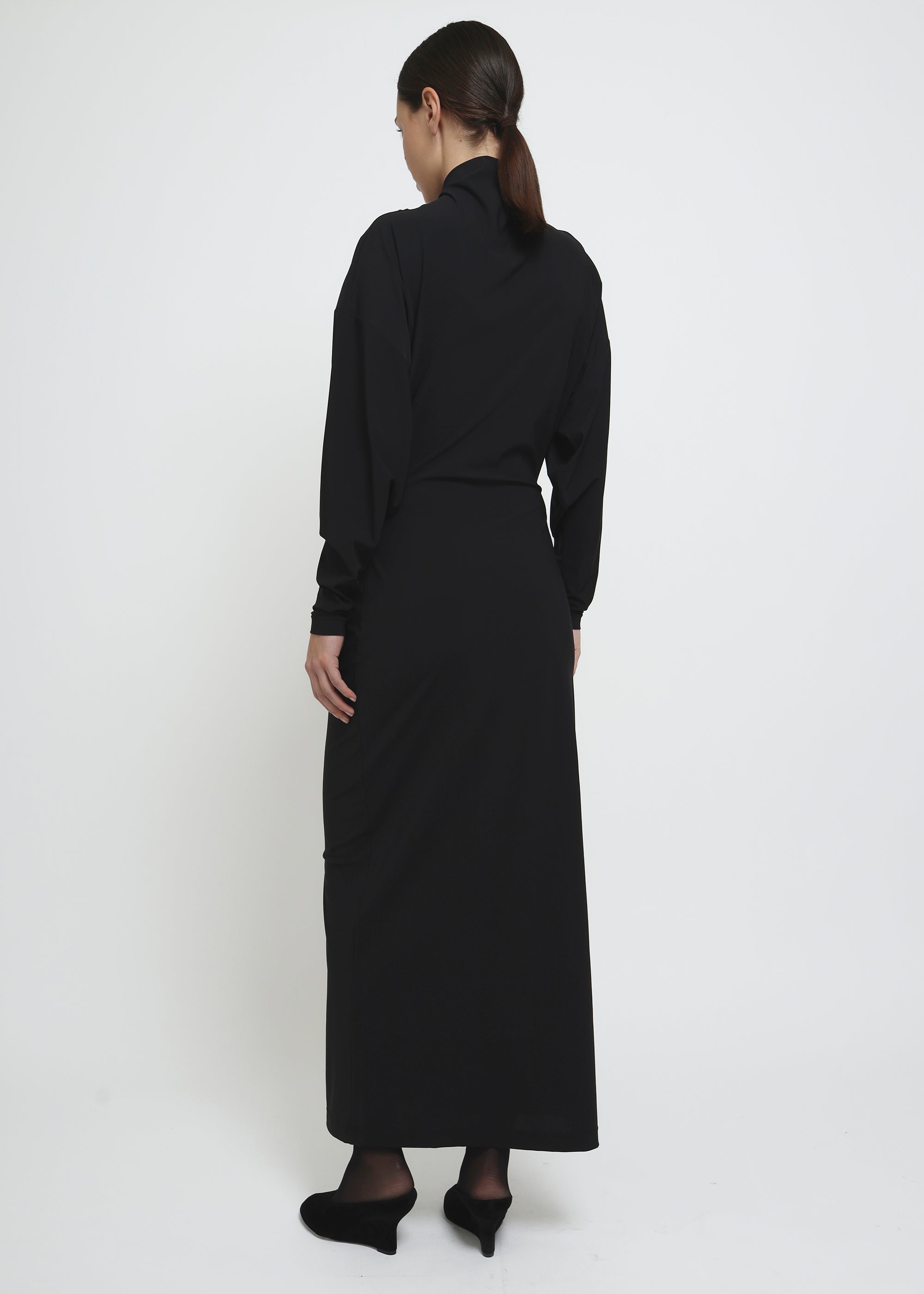 A long-sleeved black mock-neck midi dress with a draped waist.