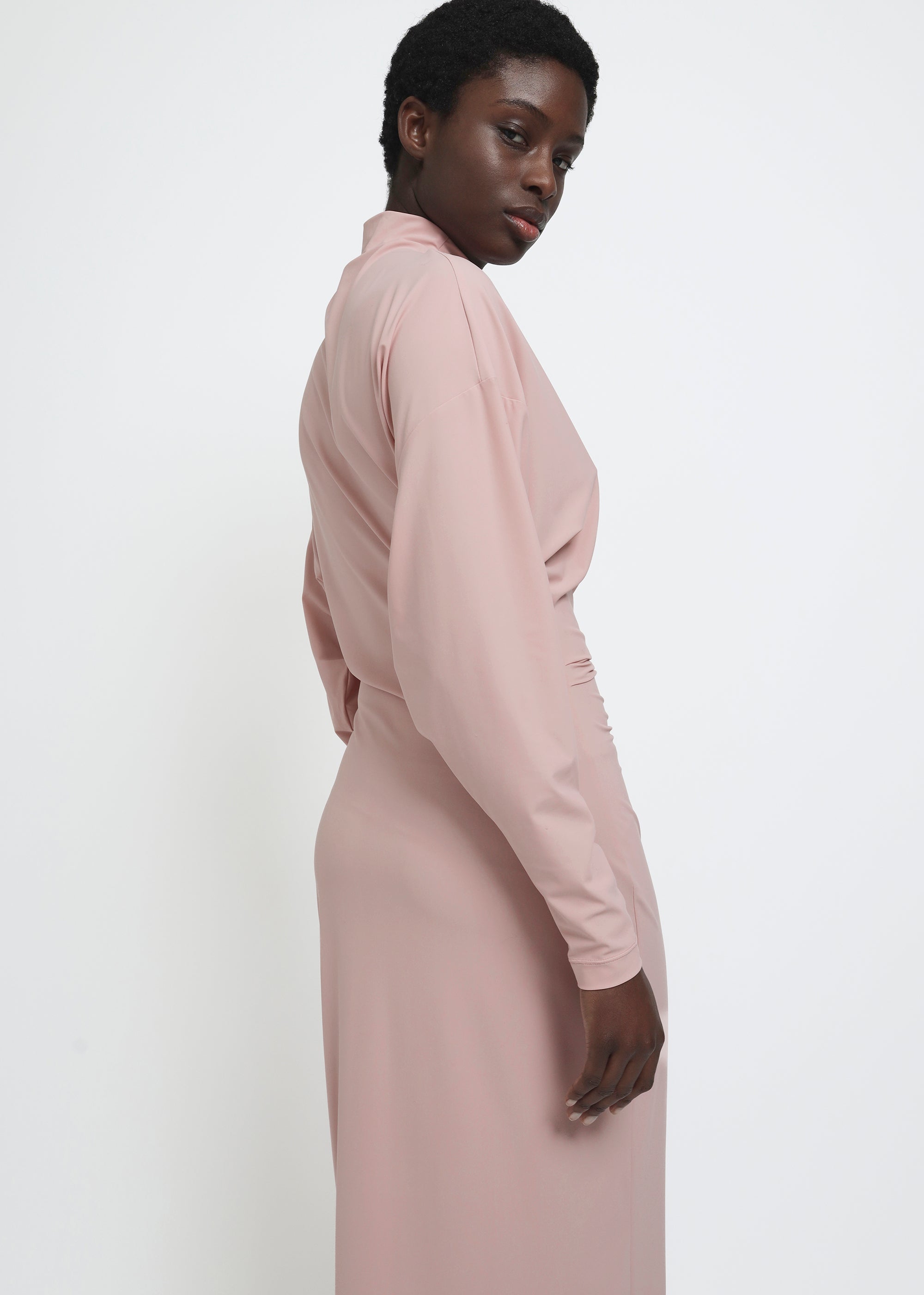 A dusty pink long-sleeve mock-neck midi dress with gathered detailing at the waist.