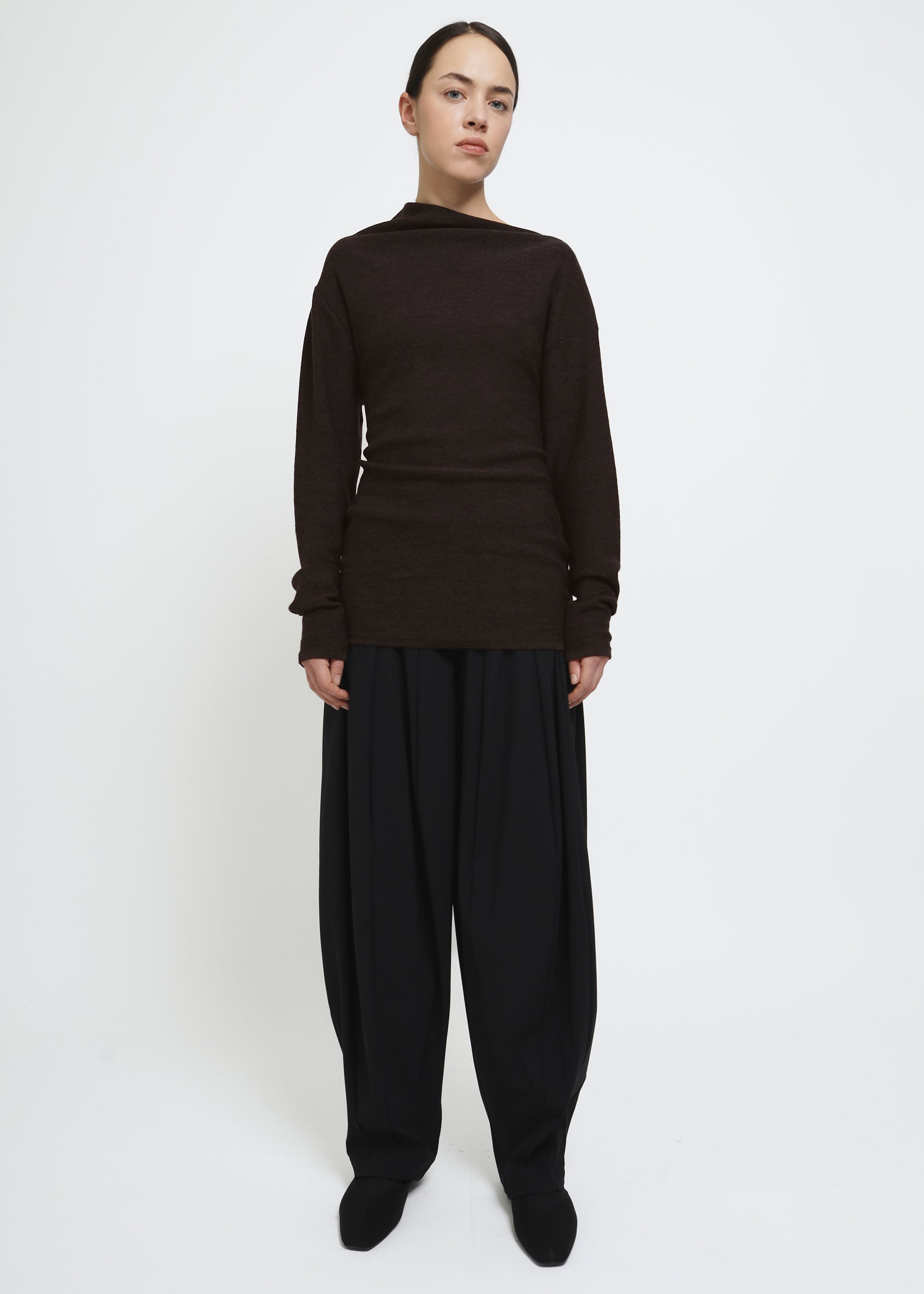 A dark brown long-sleeve knit top with a wide asymmetric neckline.