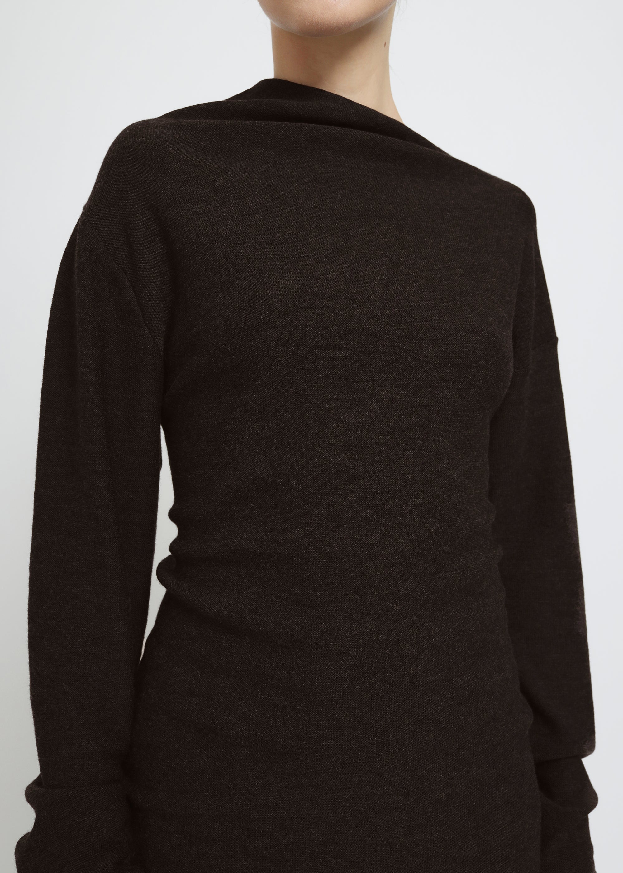 A dark brown long-sleeve knit top with a wide asymmetric neckline.