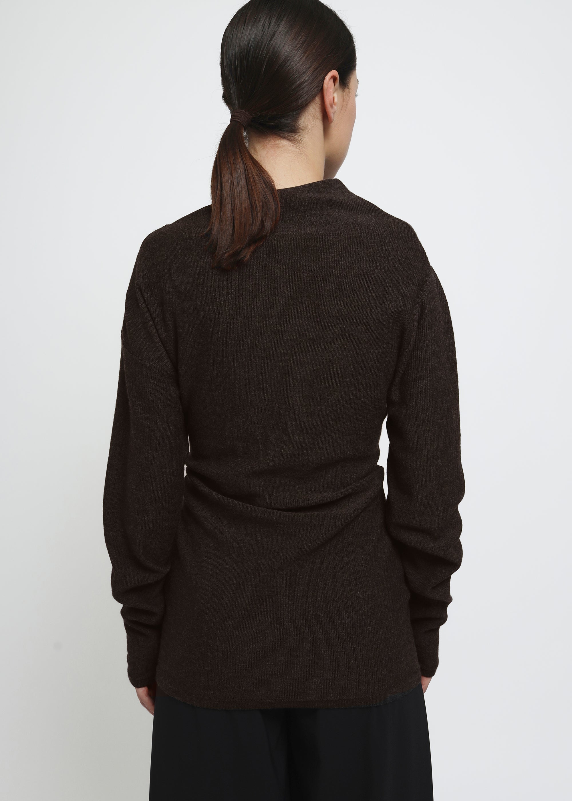 A dark brown long-sleeve knit top with a wide asymmetric neckline.