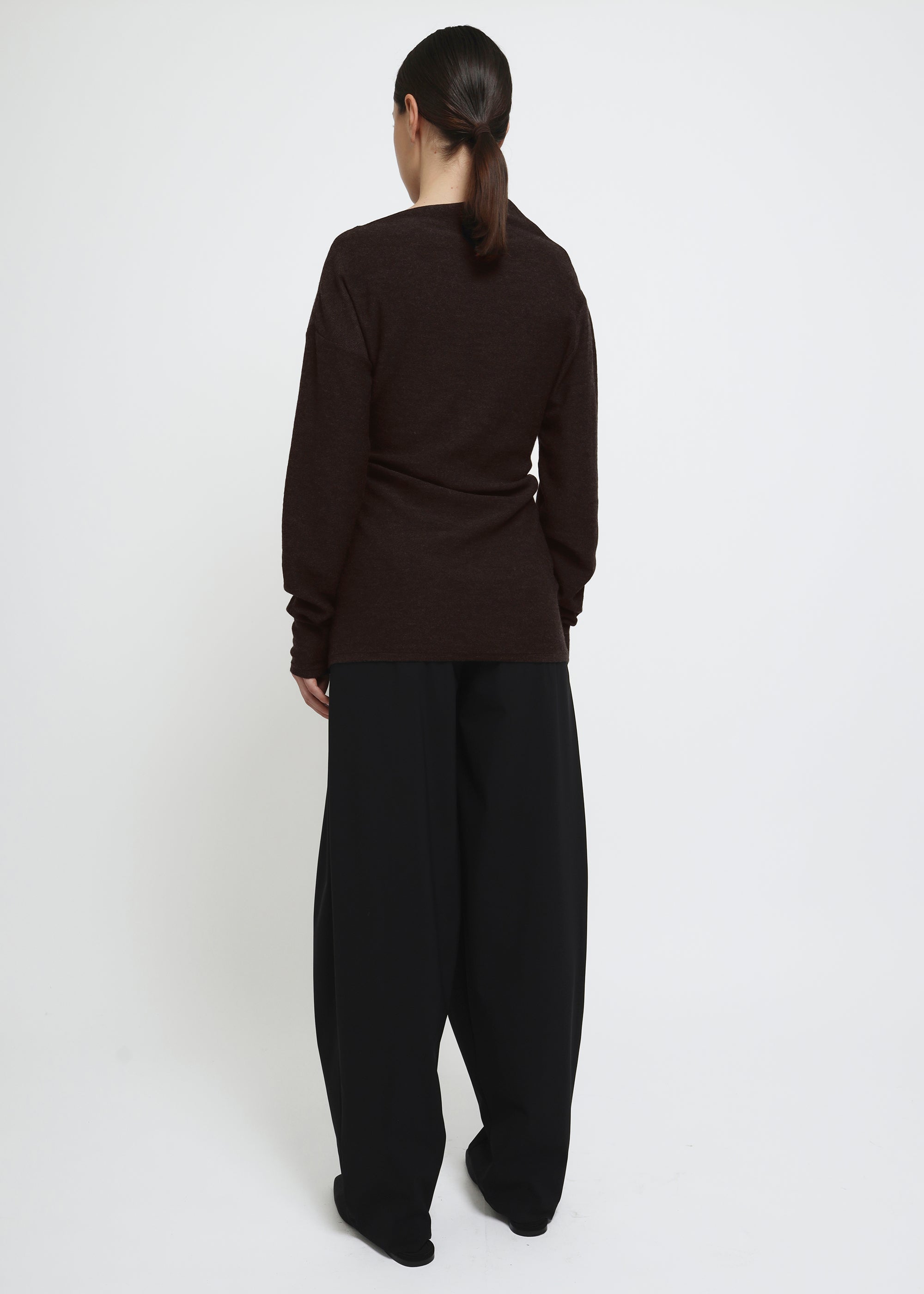 A dark brown long-sleeve knit top with a wide asymmetric neckline.