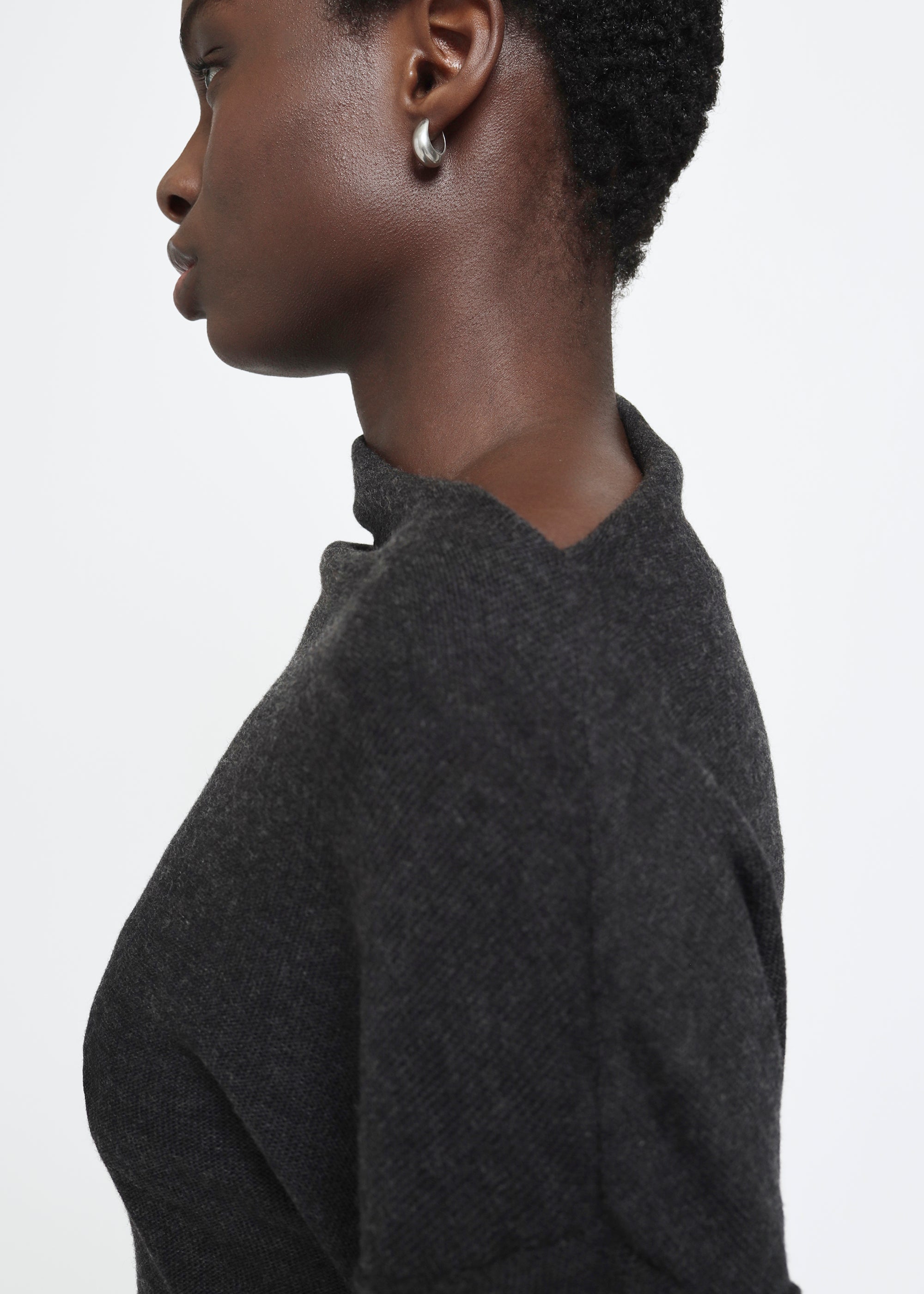 A dark gray long-sleeve knit top with a wide asymmetric neckline.