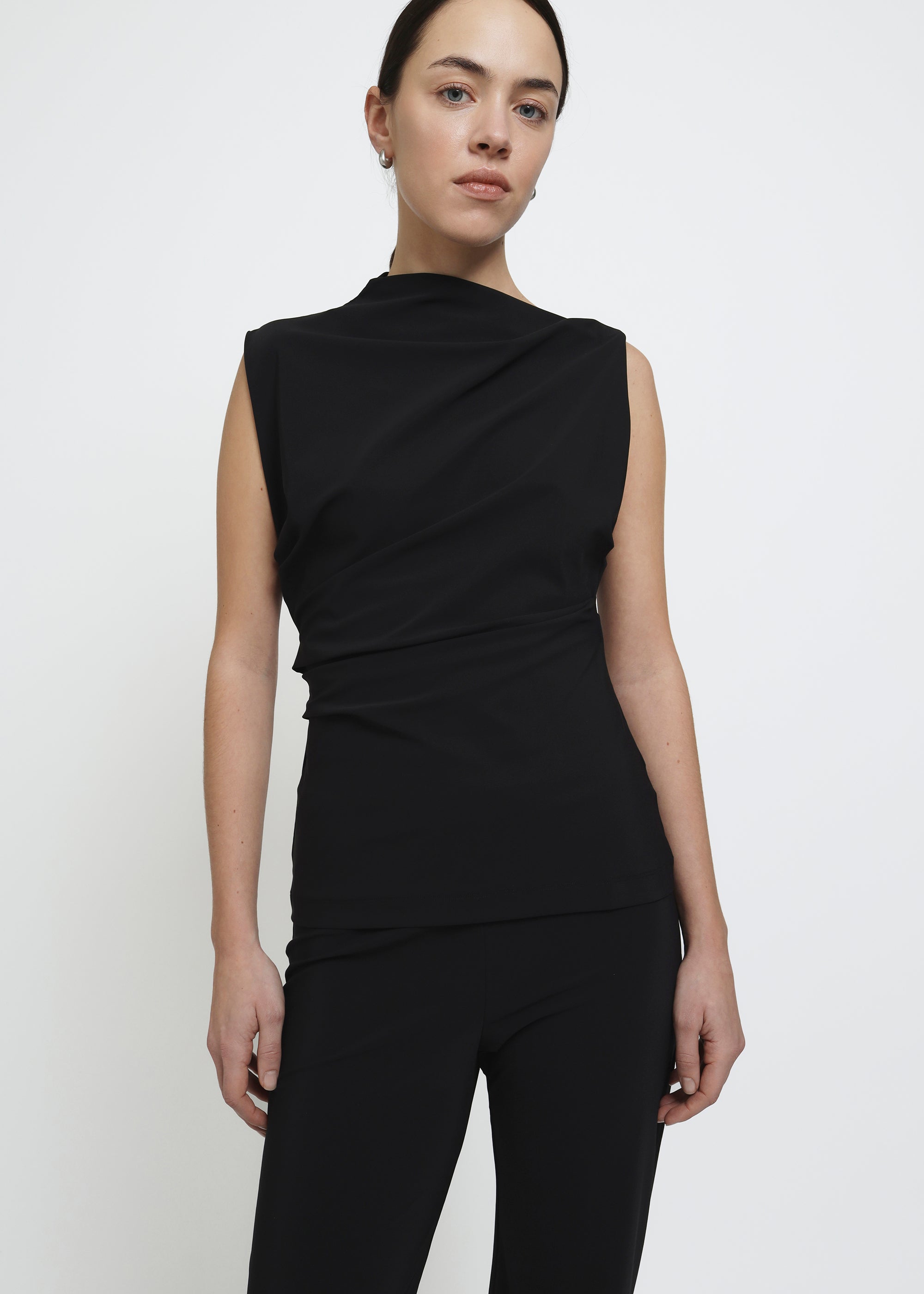 Black sleeveless top with an asymmetrical neckline and side waist folds