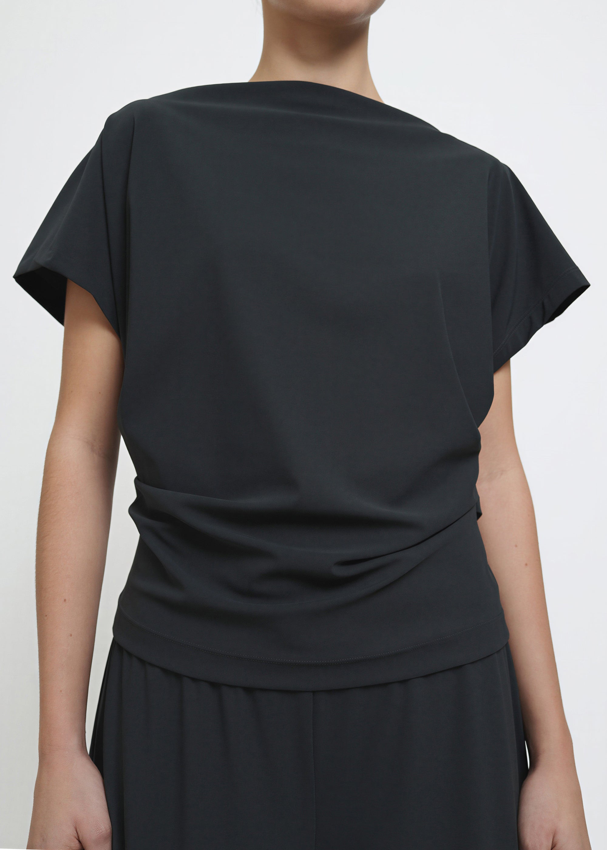 A dark grey short-sleeve top with draped fabric and a gathered waist detail.