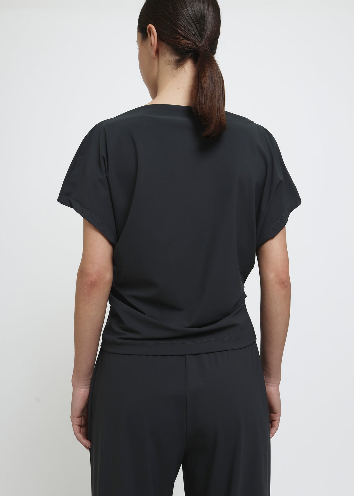 A dark grey short-sleeve top with draped fabric and a gathered waist detail.