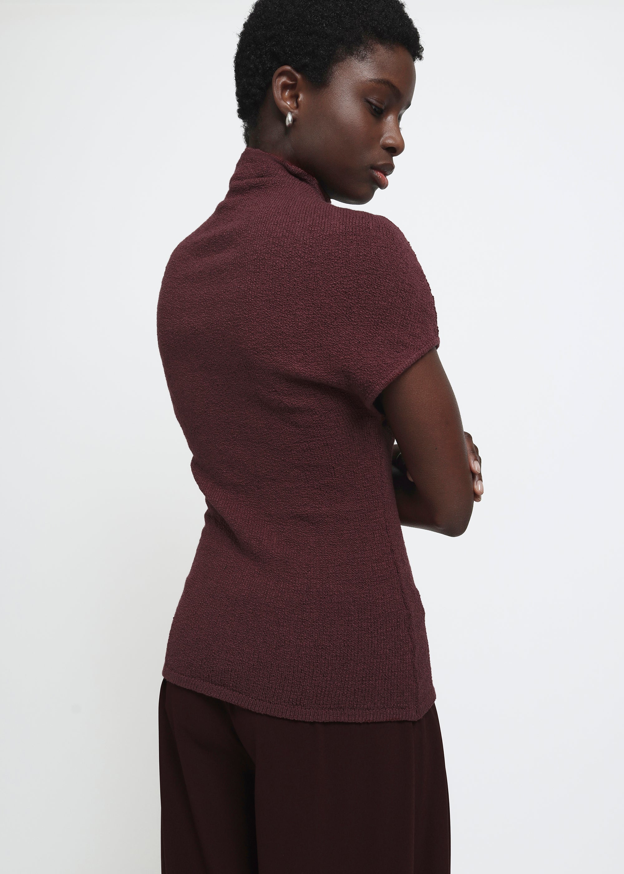 A wine colored cap-sleeve mock neck top in a textured bouclé like yarn.
