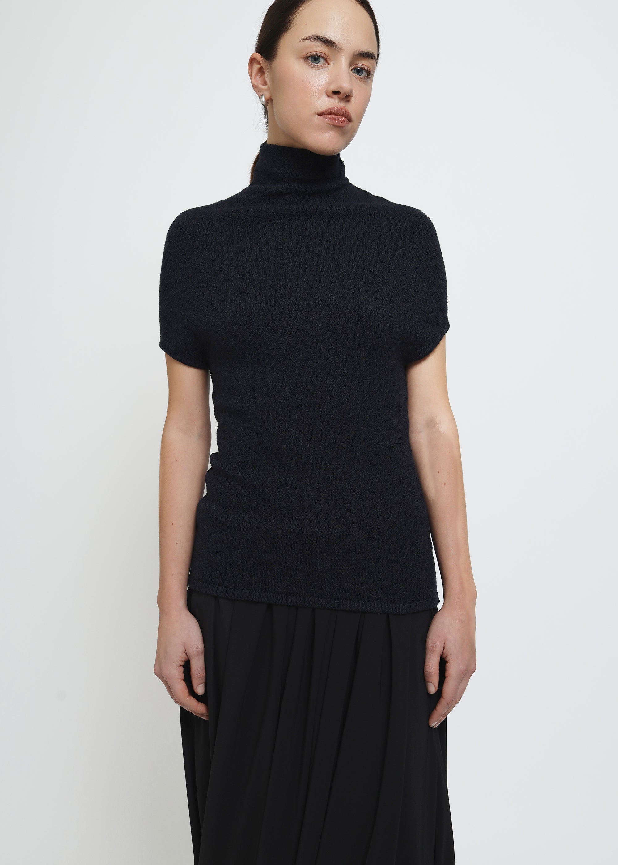 A navy cap-sleeve mock neck top in a textured bouclé like yarn.