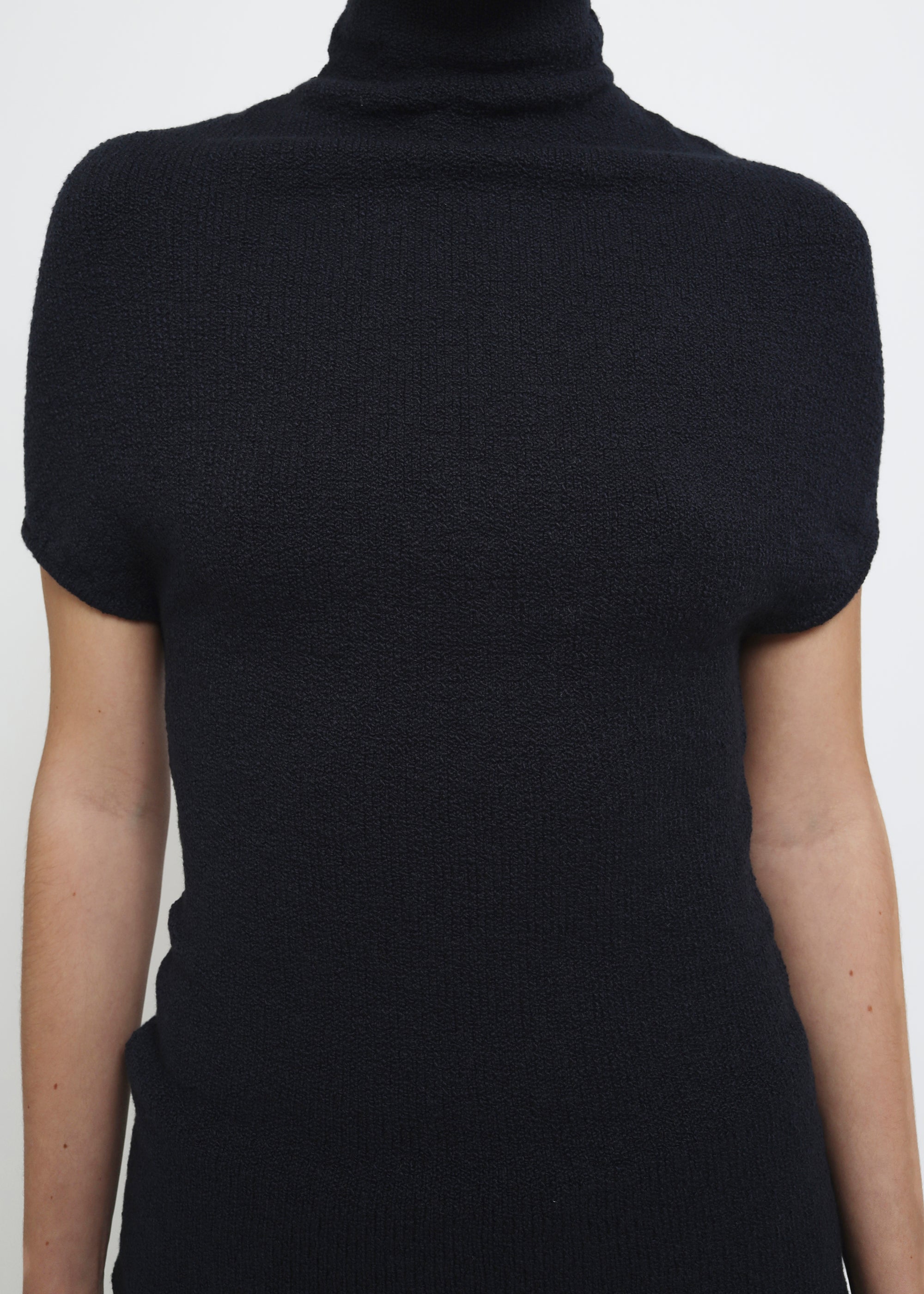 A navy cap-sleeve mock neck top in a textured bouclé like yarn.