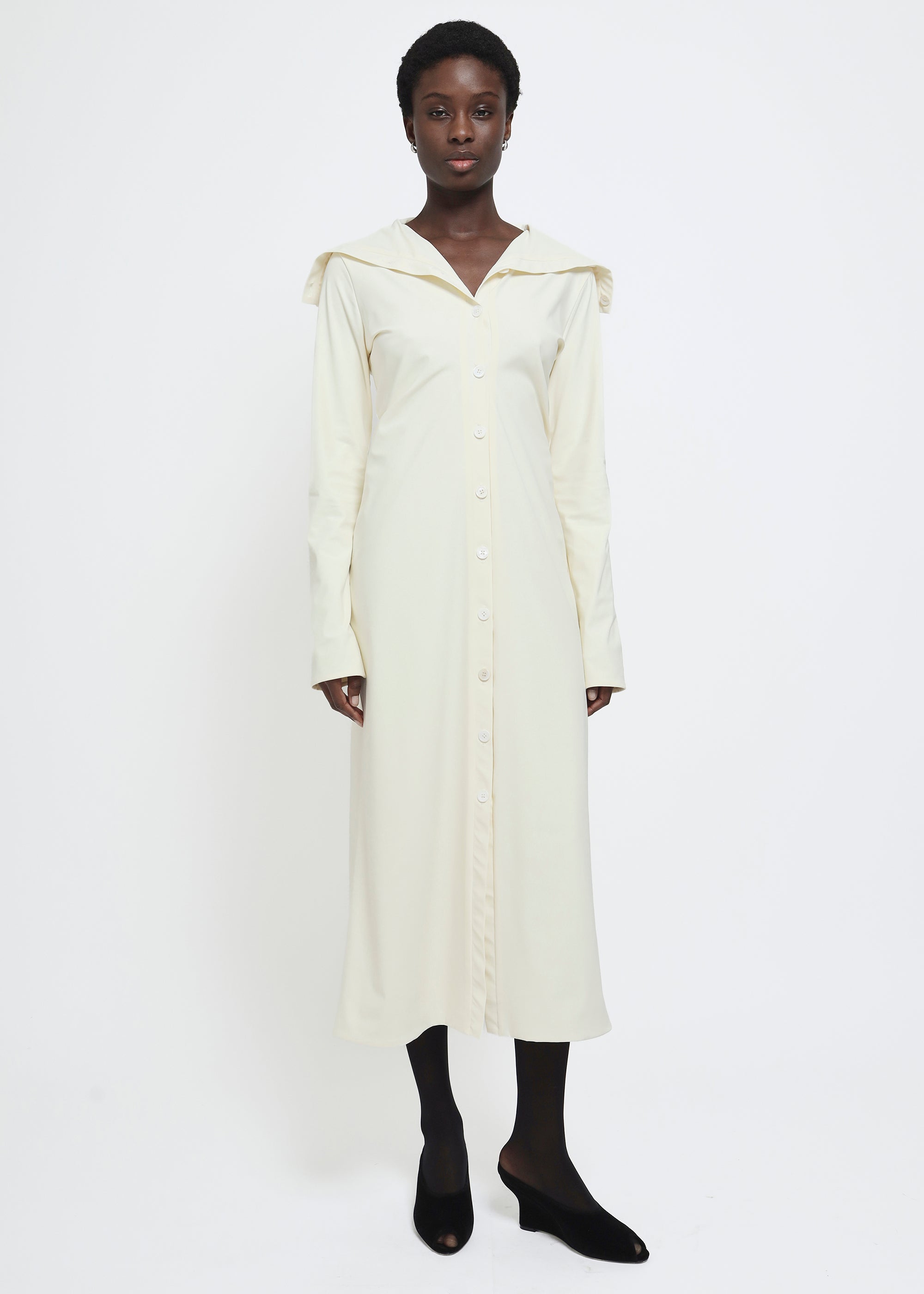 A long-sleeved cream-colored button-up dress with a wide collar.