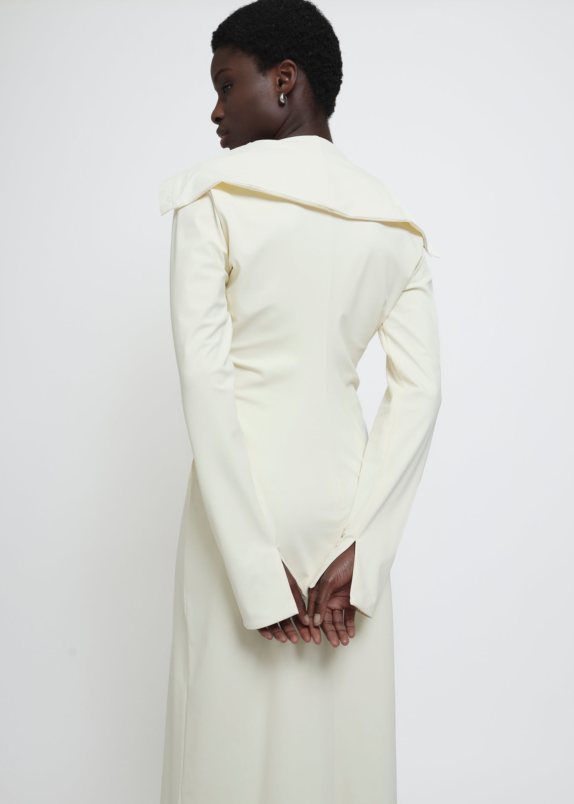 A long-sleeved cream-colored button-up dress with a wide collar.