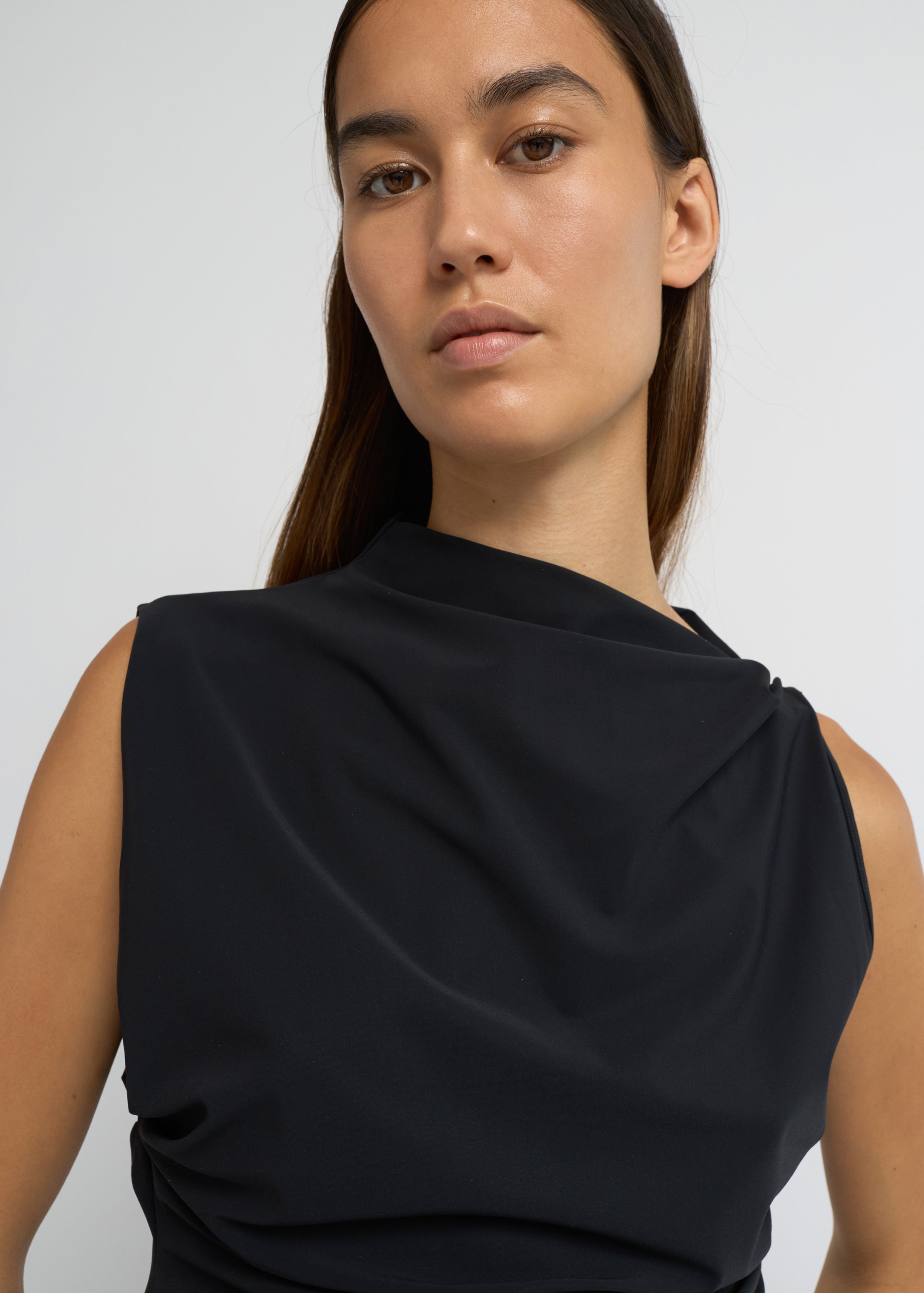 Black sleeveless top with an asymmetrical neckline and side waist folds