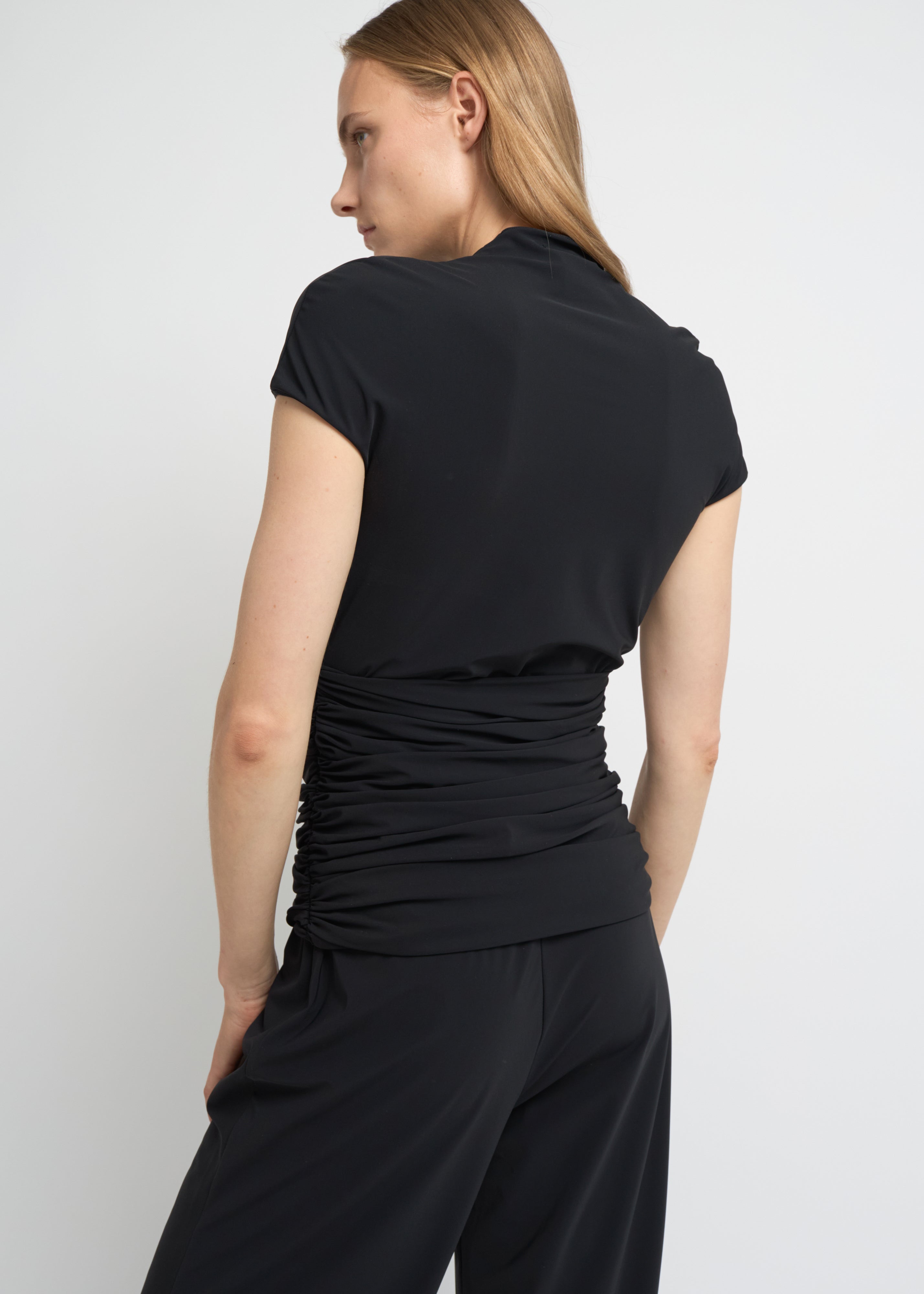 Black fitted short-sleeve top with a high neckline and soft gathers at the waist