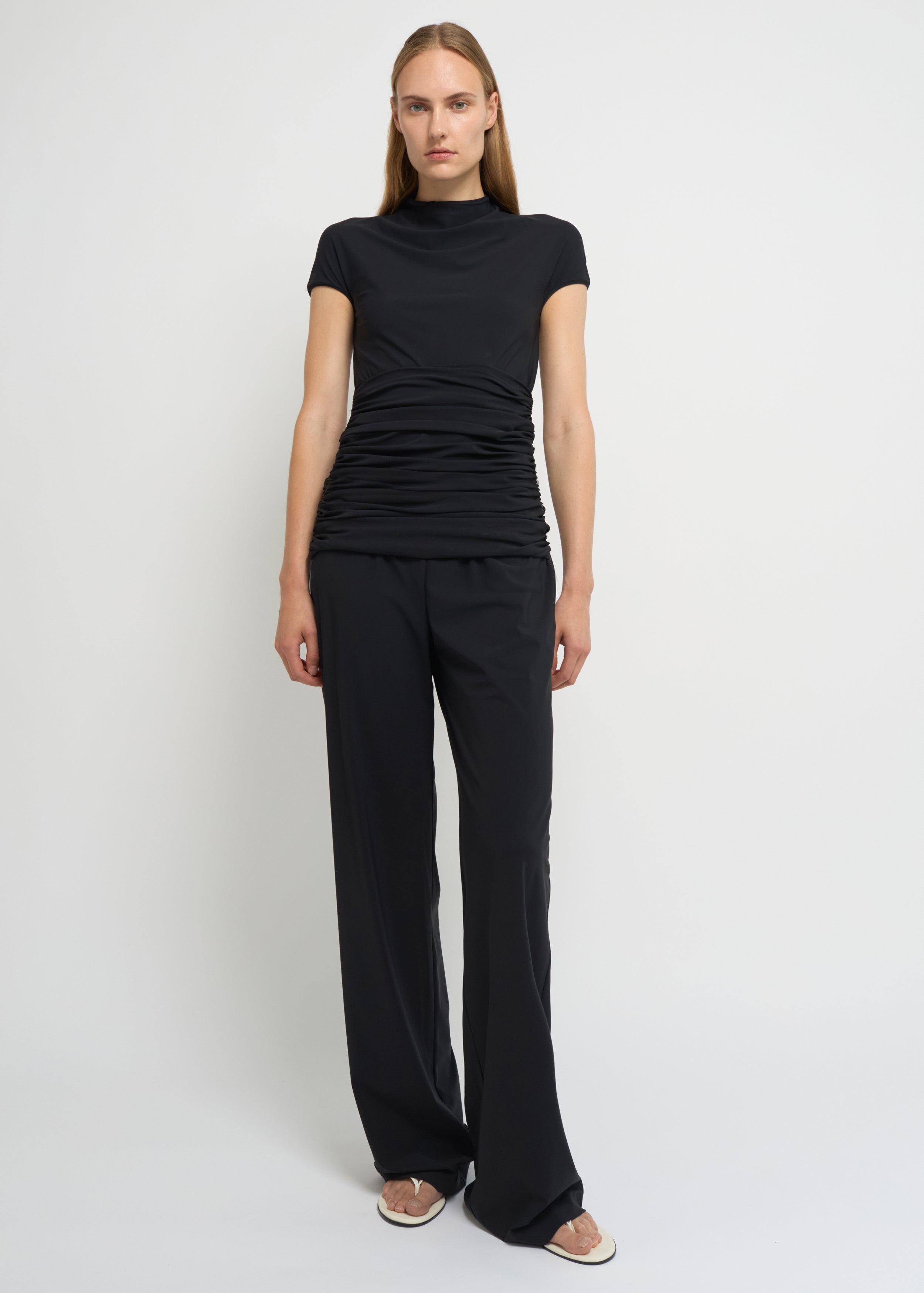 Black fitted short-sleeve top with a high neckline and soft gathers at the waist