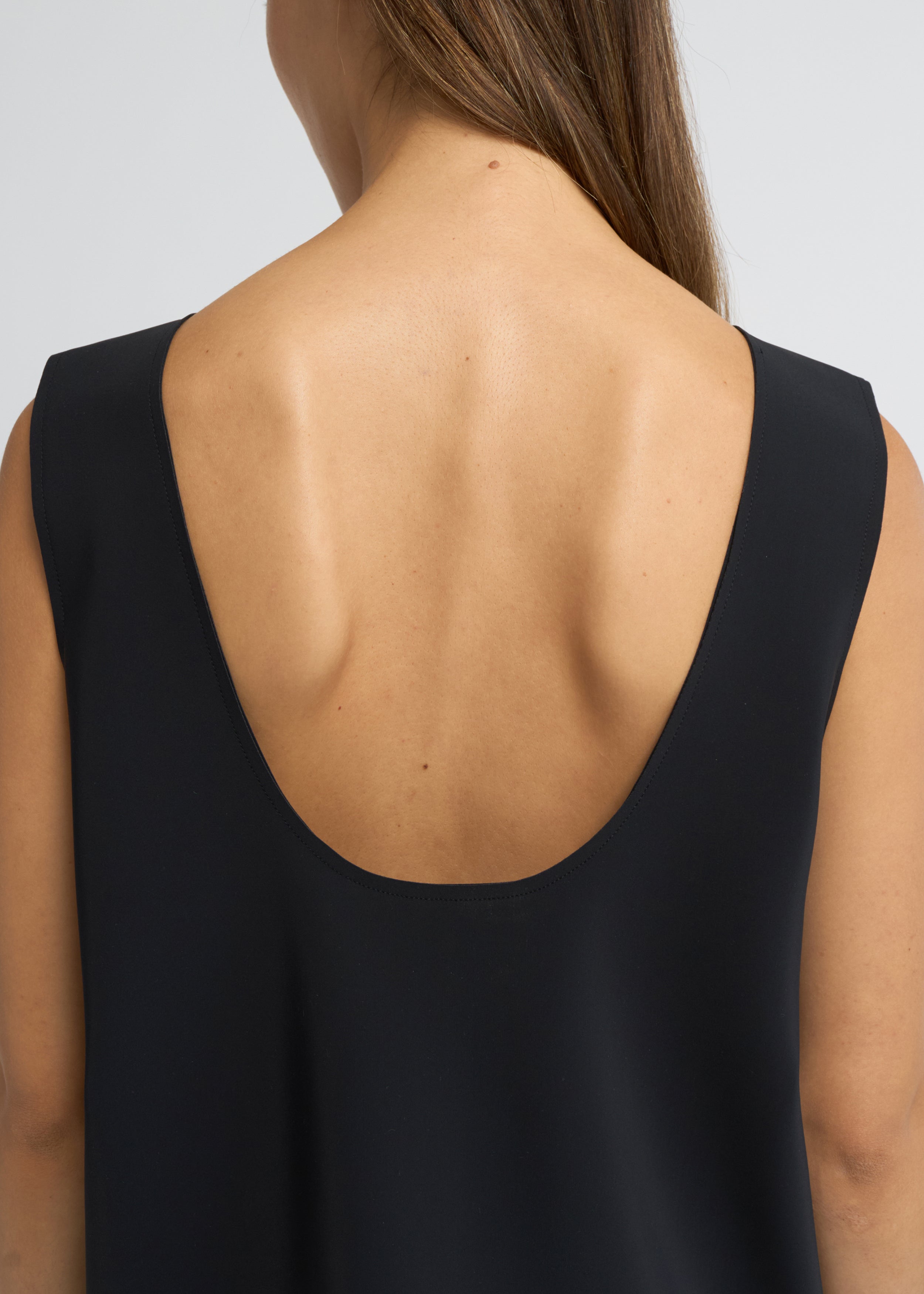 Black sleeveless scoop-neck top with a structured, elongated line